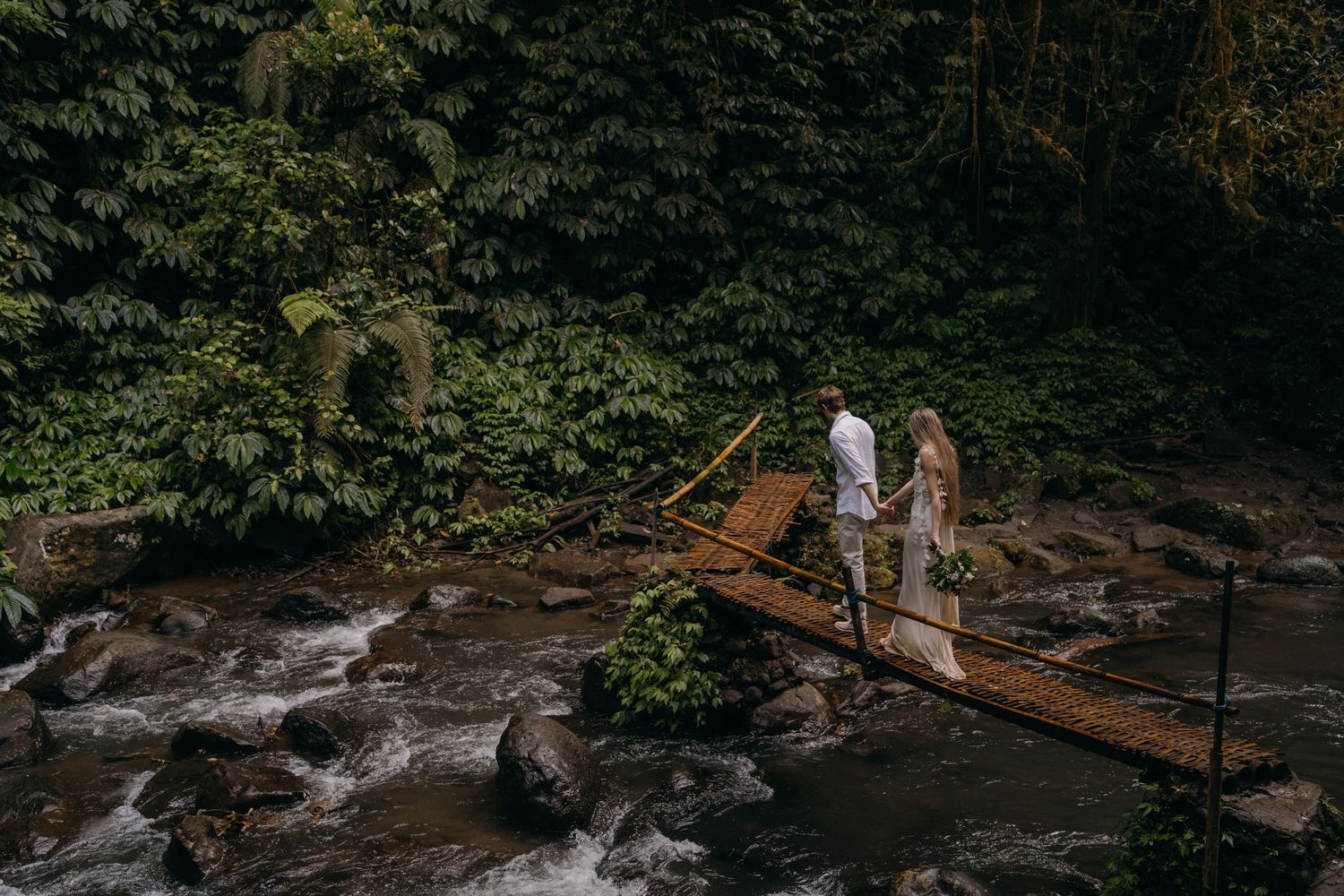 A group of people explore a scenic waterfall trail surrounded by lush forest and rocky terrain.