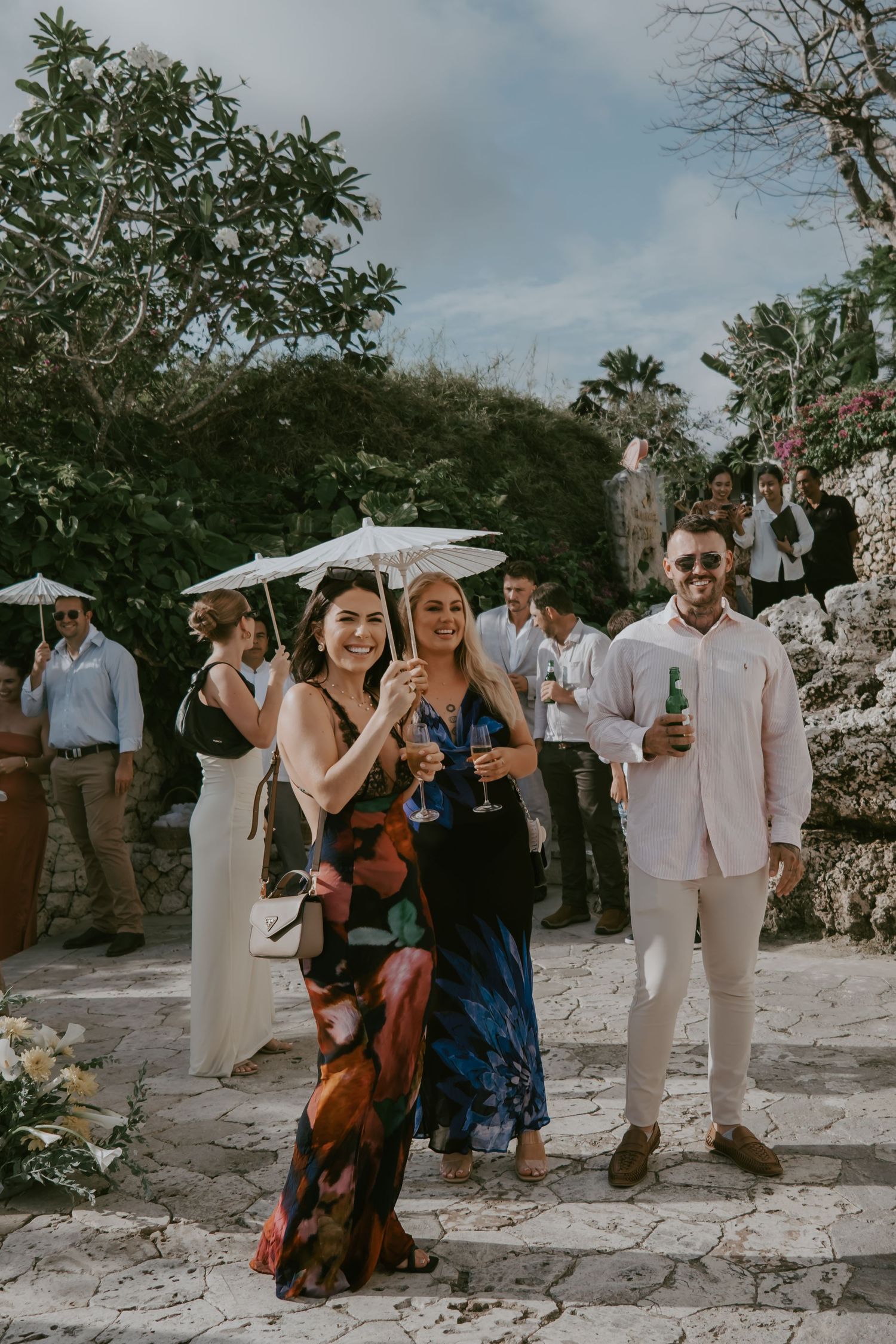Wedding guests mingling at an outdoor reception on a stone terrace.