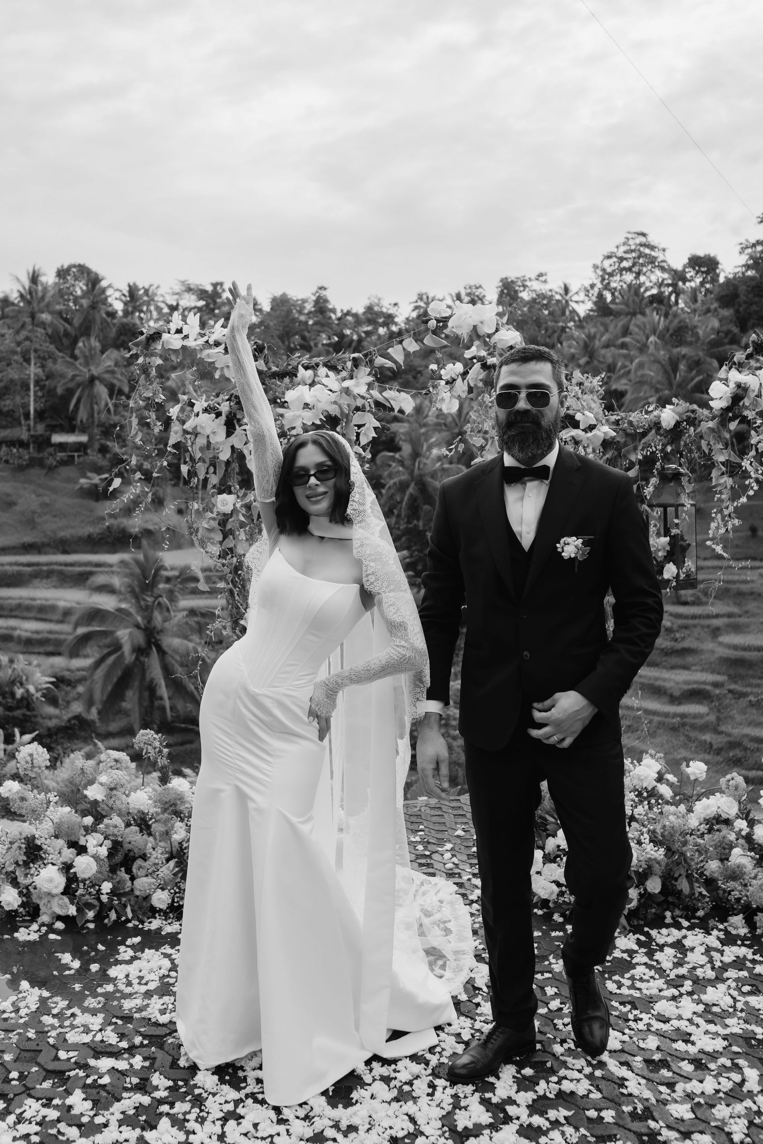 A black and white photo series of a bride and groom posing together in a garden filled with blooming flowers.