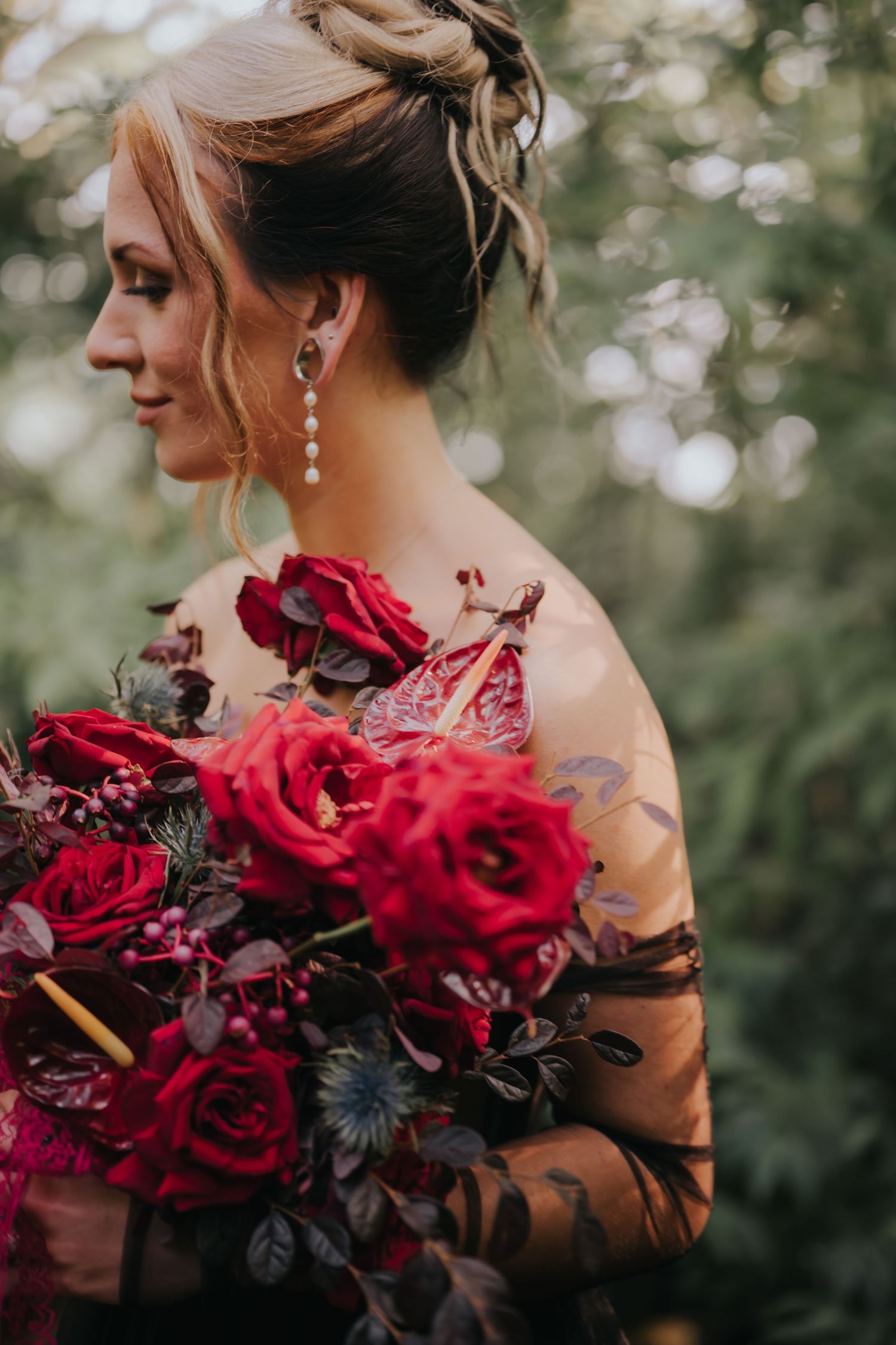 Elegant bridal bouquet featuring rich red roses and dark foliage with sheer black details.