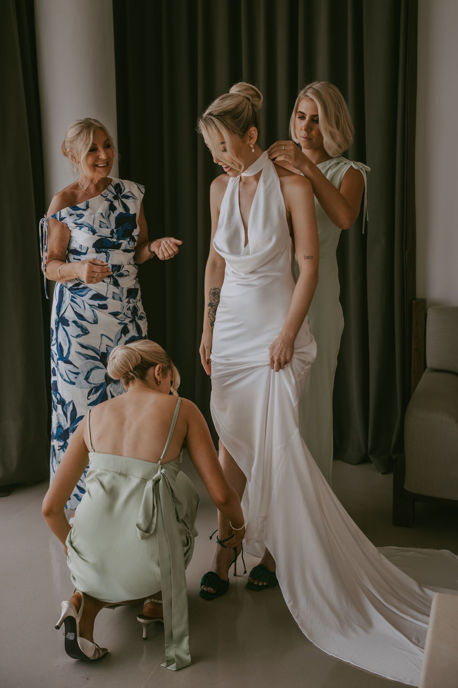 Wedding dress being adjusted and fitted in a dimly lit dressing room.