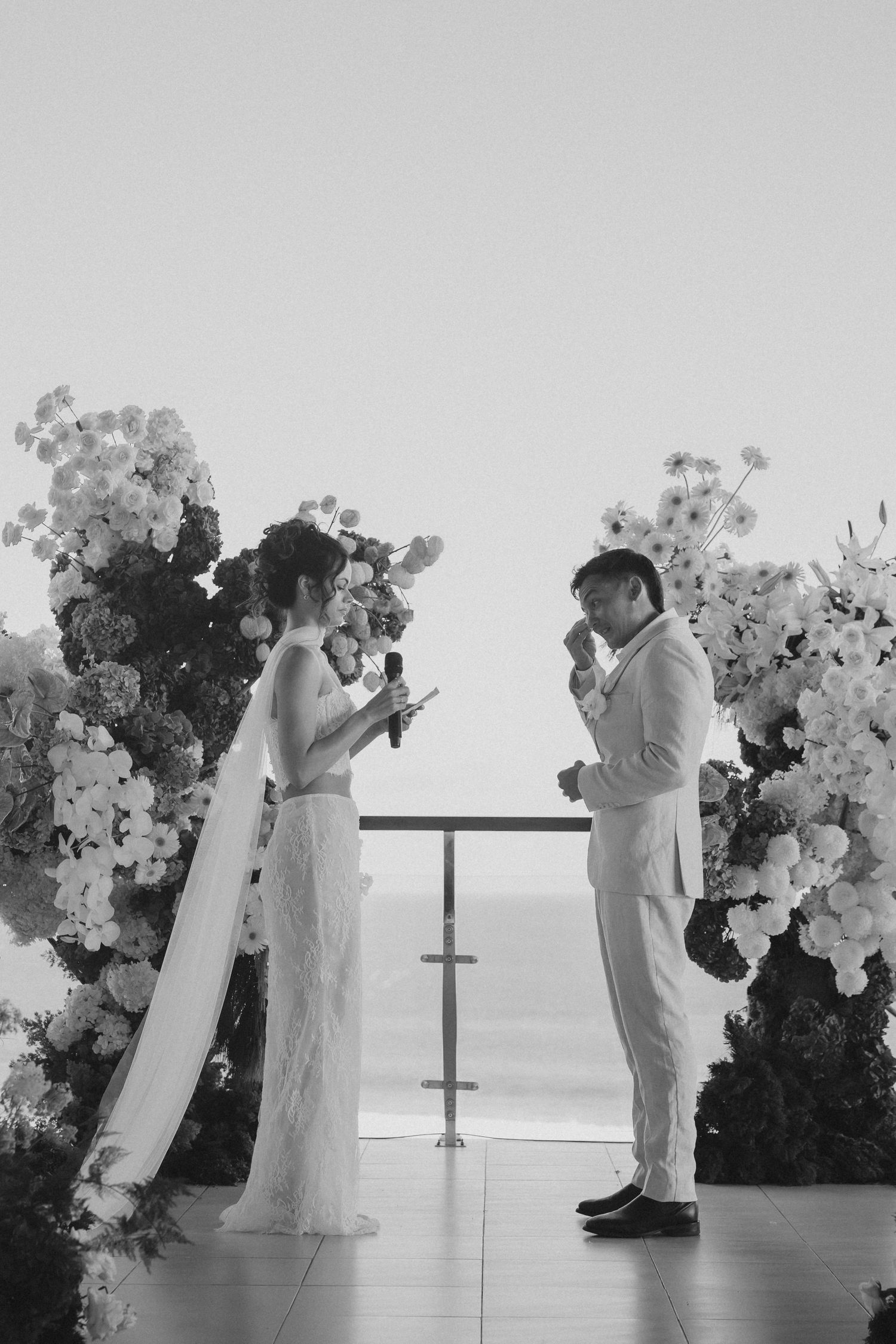 A wedding ceremony sequence showing a couple getting married against a floral arch backdrop by the ocean.