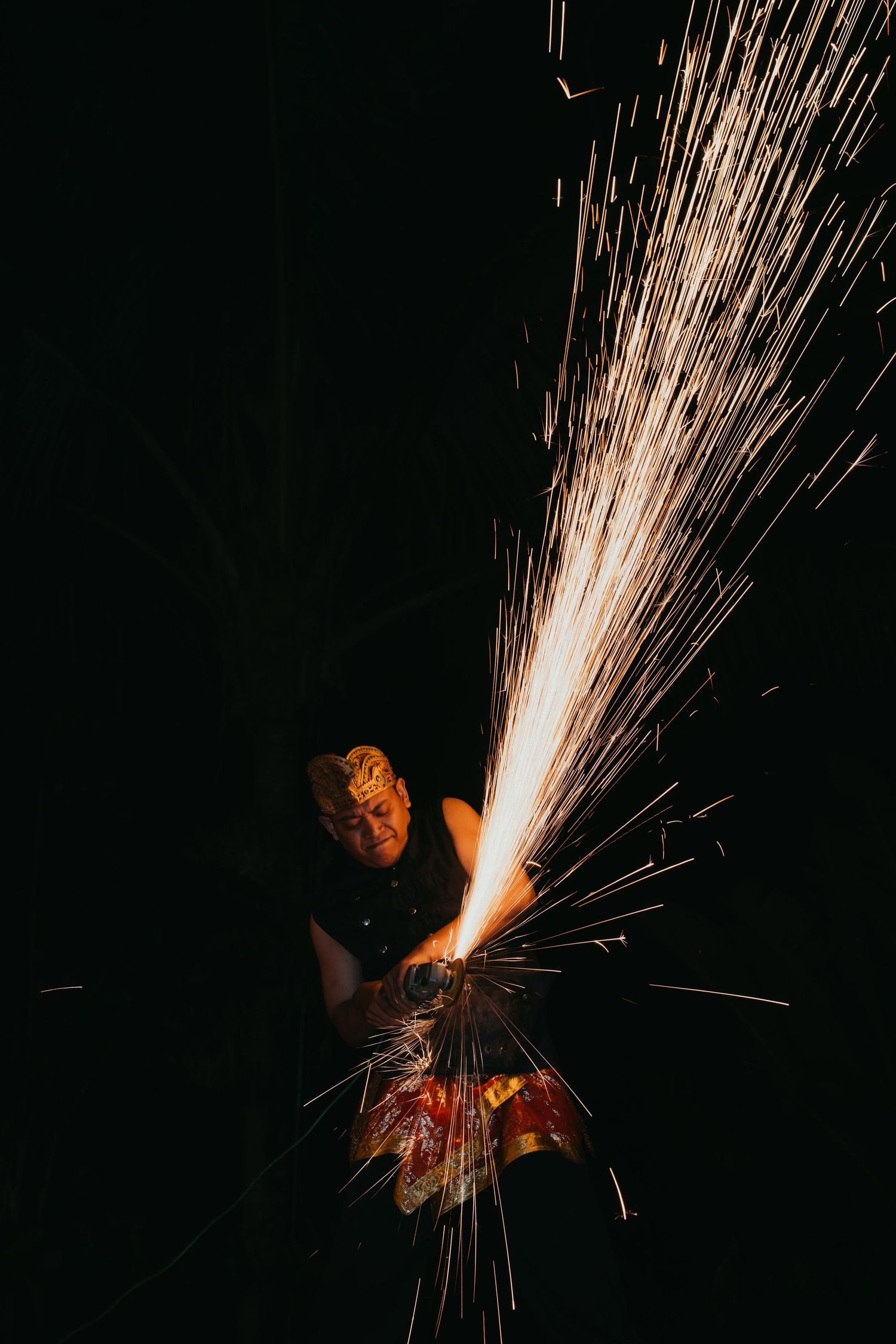 Fire performer creating dramatic sparks display against dark background at wedding entertainment show.