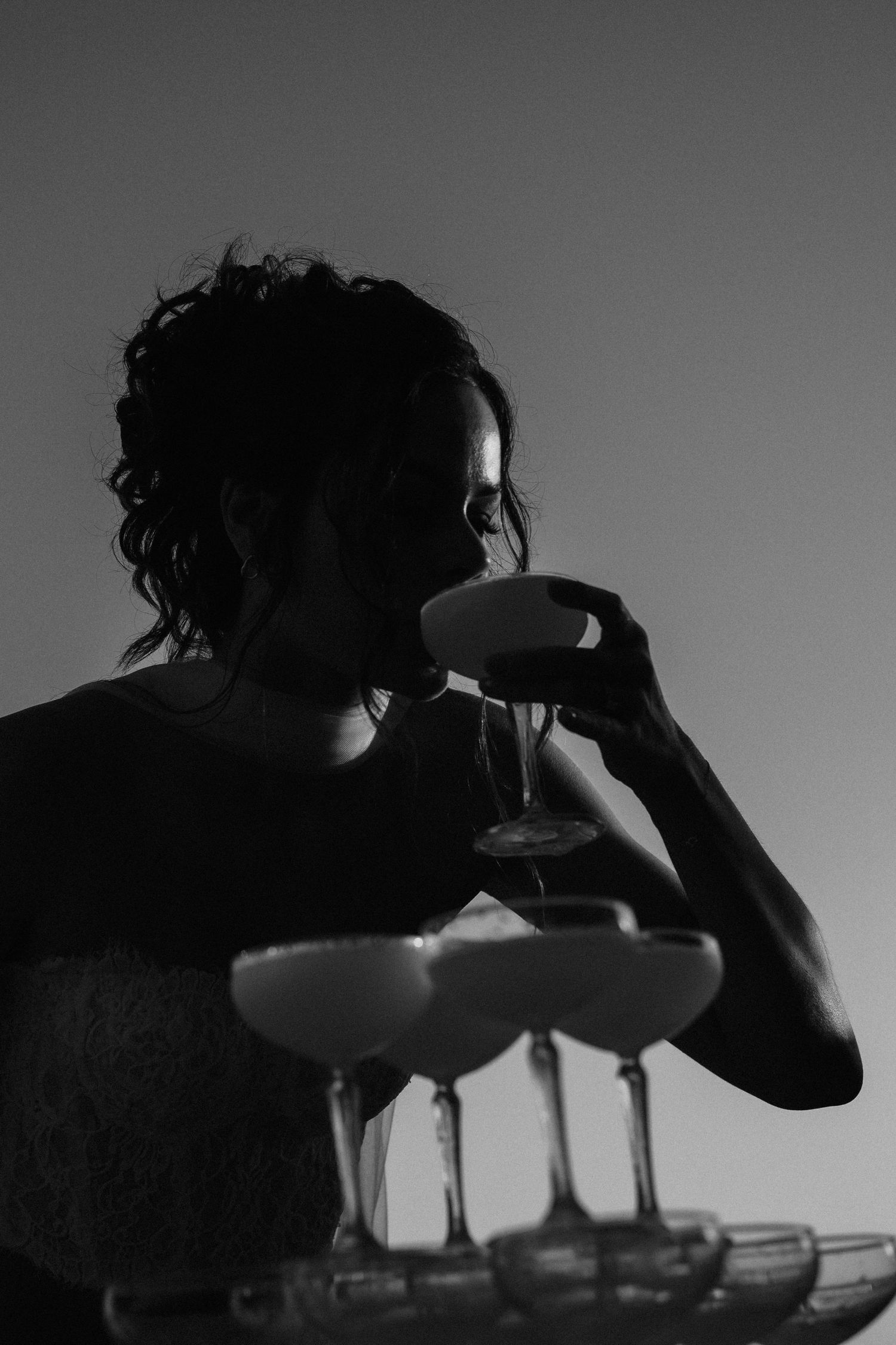 Silhouetted figure drinking from a mug against a dramatic sky in black and white.