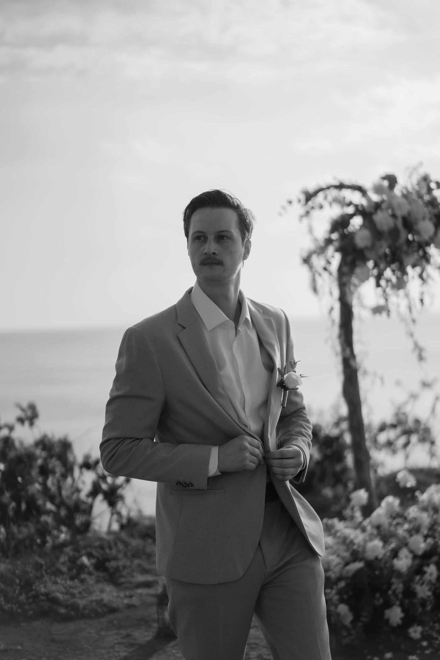 A person in a light-colored suit stands outdoors in a series of black and white photographs.