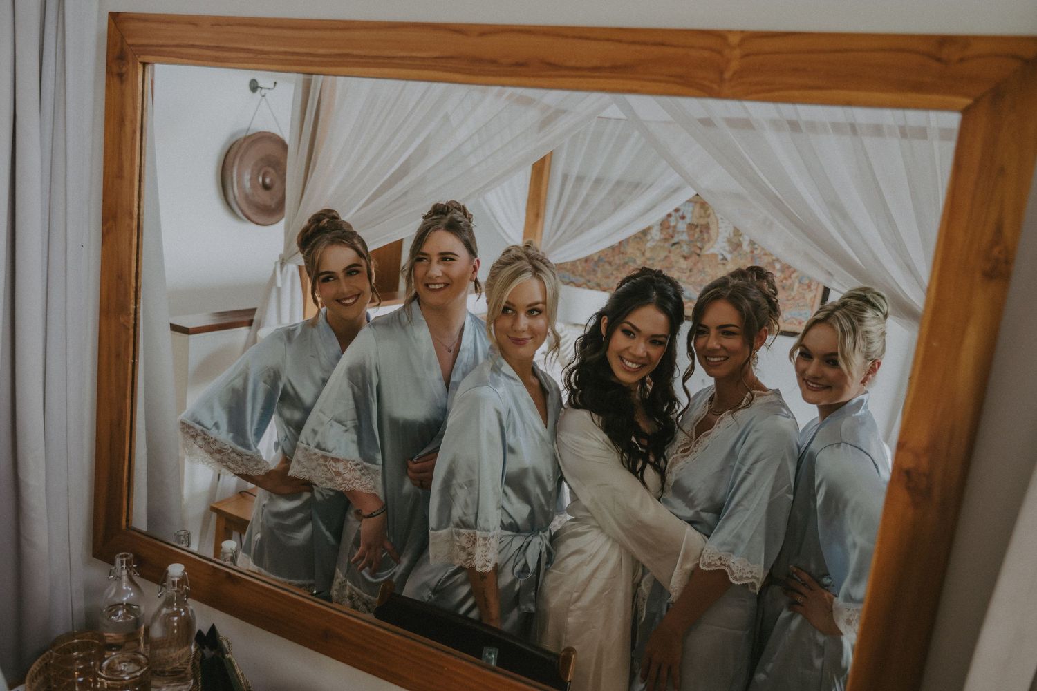 Wedding party getting ready in matching gray robes in a bright room.