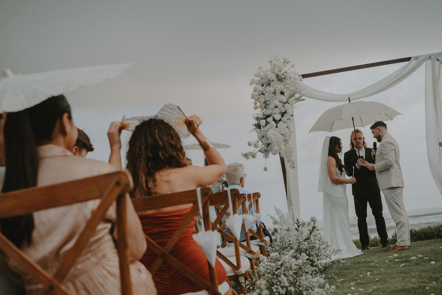 Wedding guests dance and celebrate under a white tent at an outdoor reception during sunset.