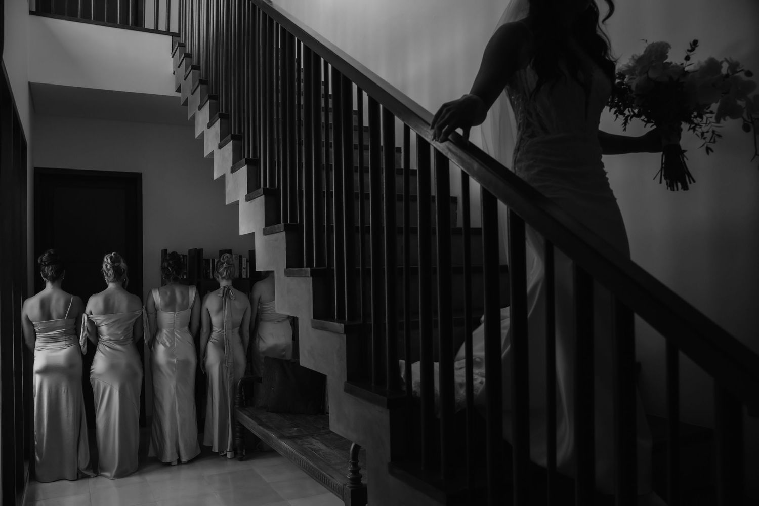 Dramatic black and white photograph showing silhouettes of figures standing on a staircase with iron railings.