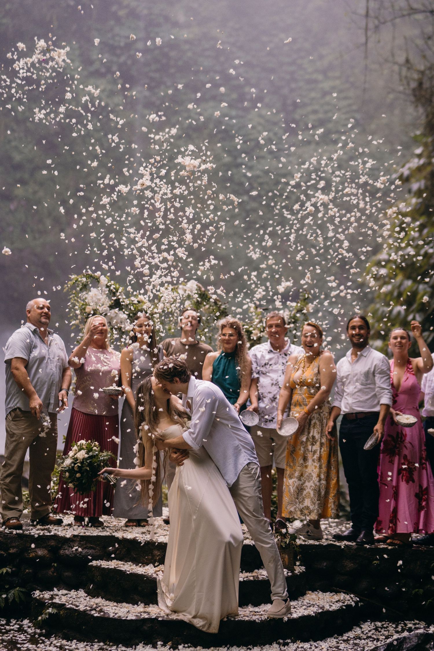 A couple shares a romantic moment during their outdoor wedding celebration as confetti rains down around them.