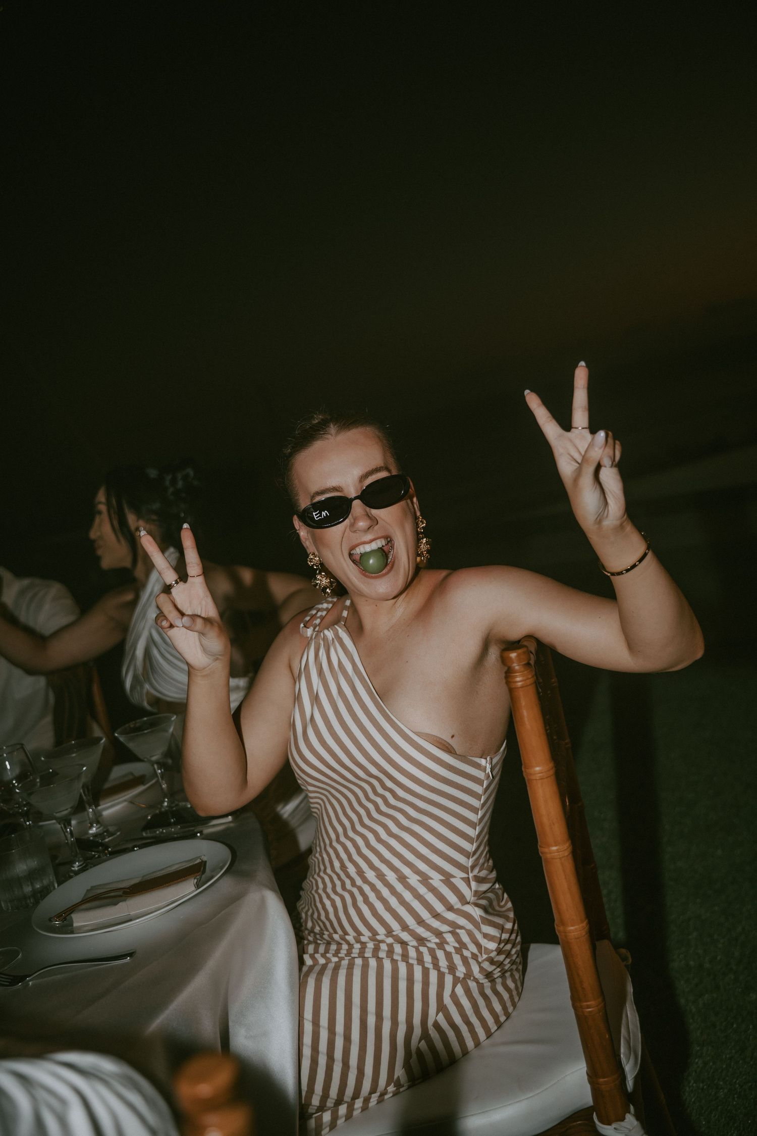 A person in a striped dress sits in a chair making animated expressions and gestures in a sequence of photos.