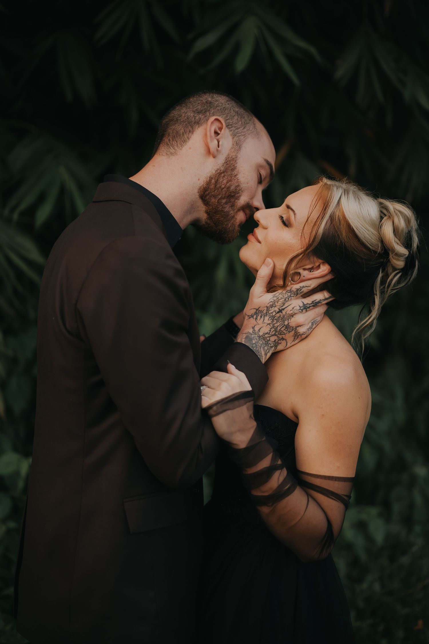 Romantic couple shares intimate moments in a dark outdoor setting wearing formal attire.