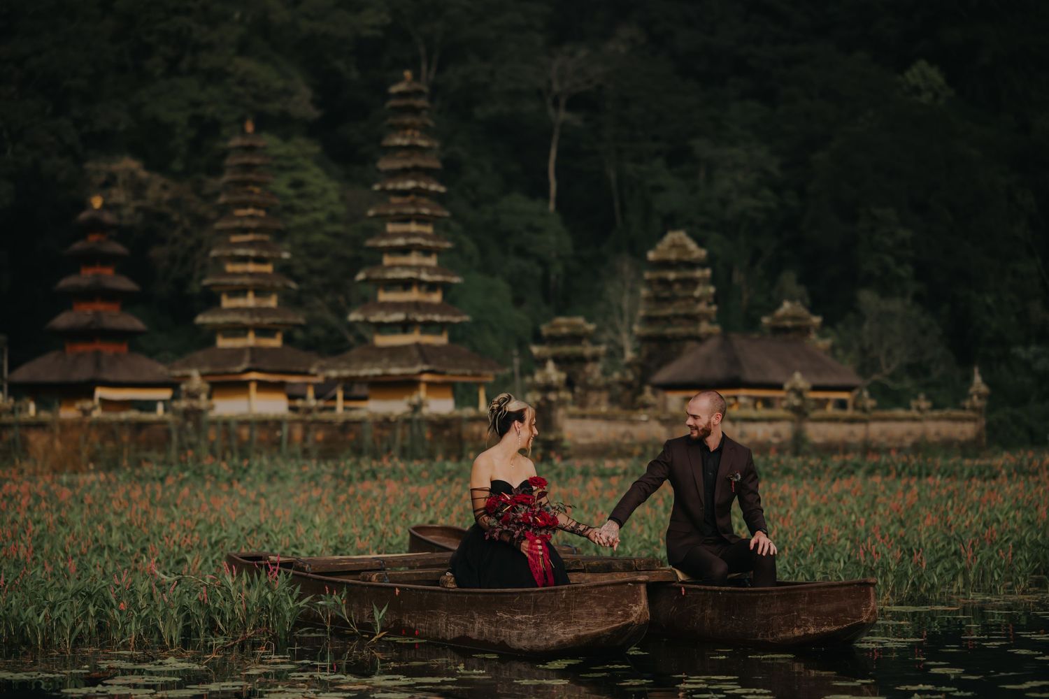 A couple poses in front of traditional pagoda structures in a scenic outdoor setting.