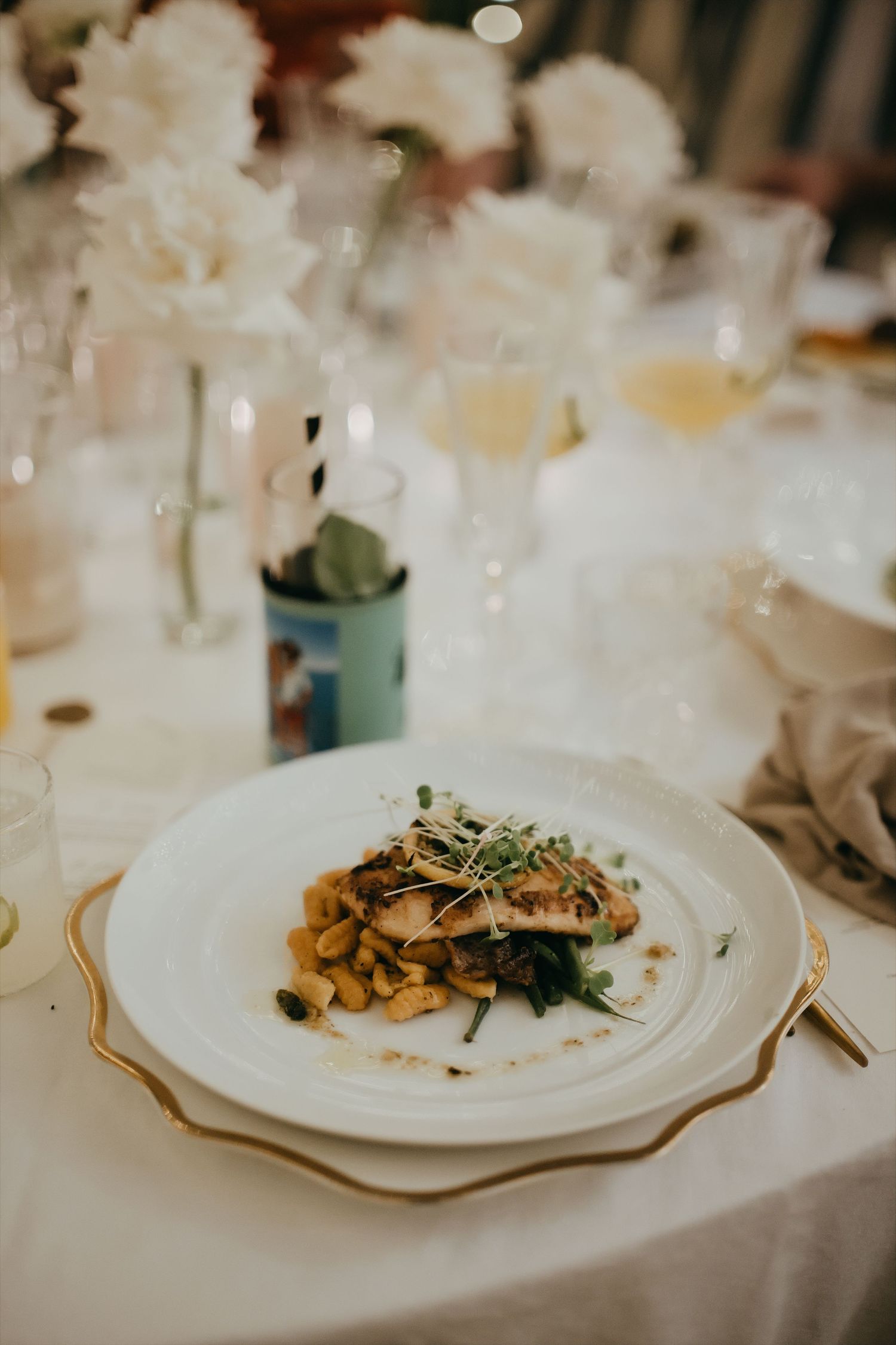Elegant wedding reception plate with gourmet cuisine served on white and gold dinnerware.