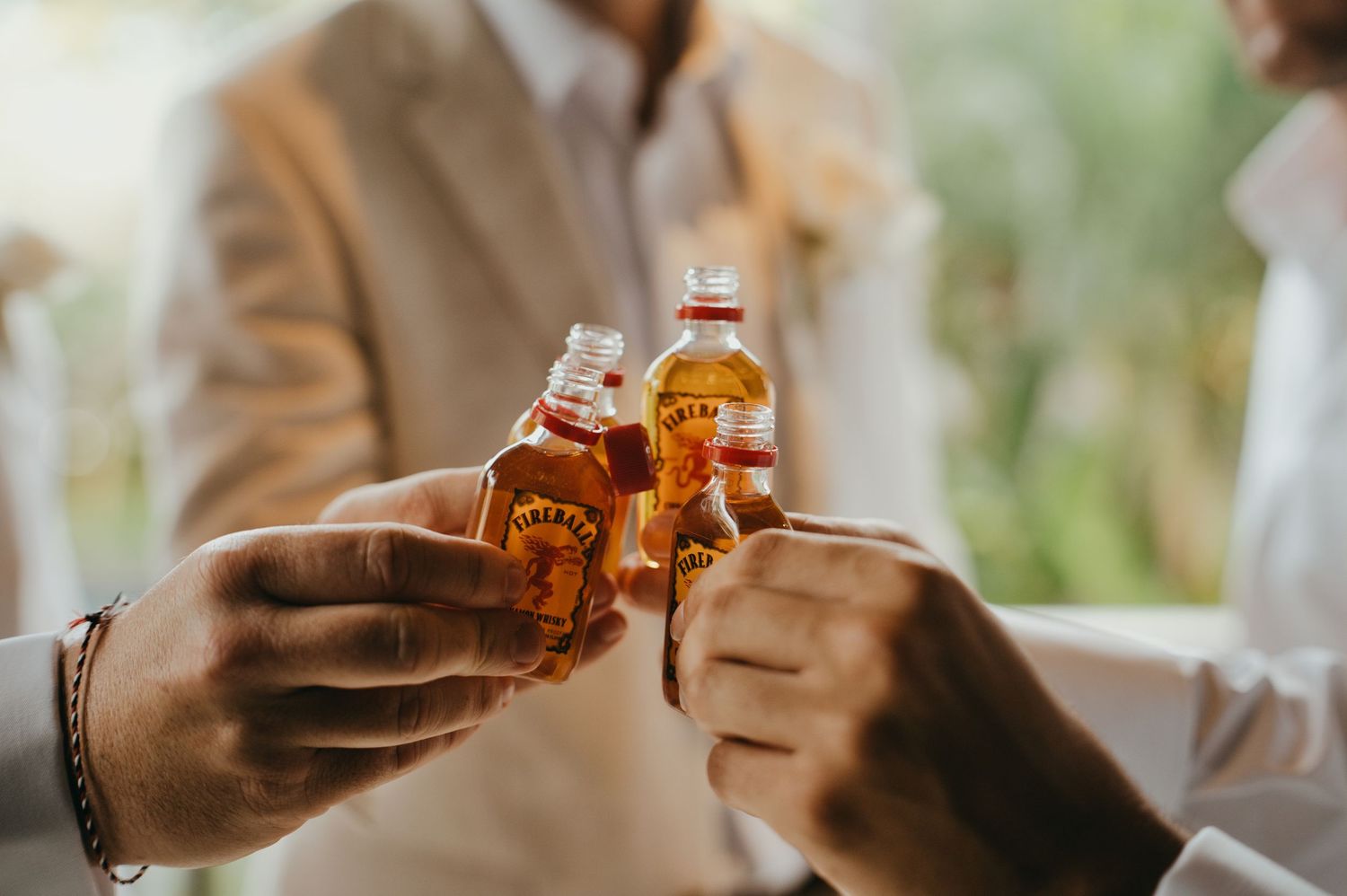 Groomsmen toasting with mini Fireball whiskey bottles before a wedding ceremony.
