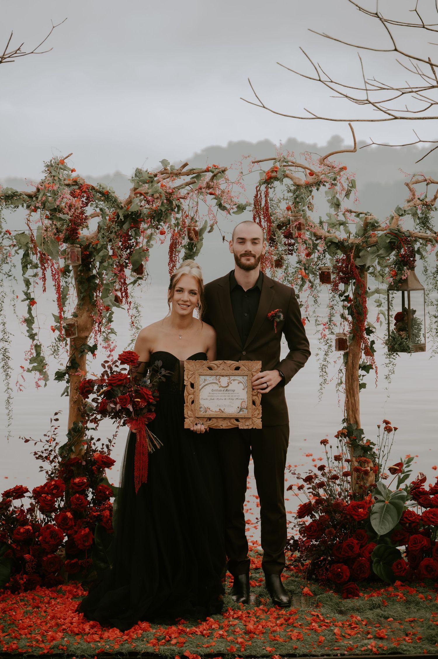 Romantic wedding ceremony space decorated with hanging florals and scattered red petals.