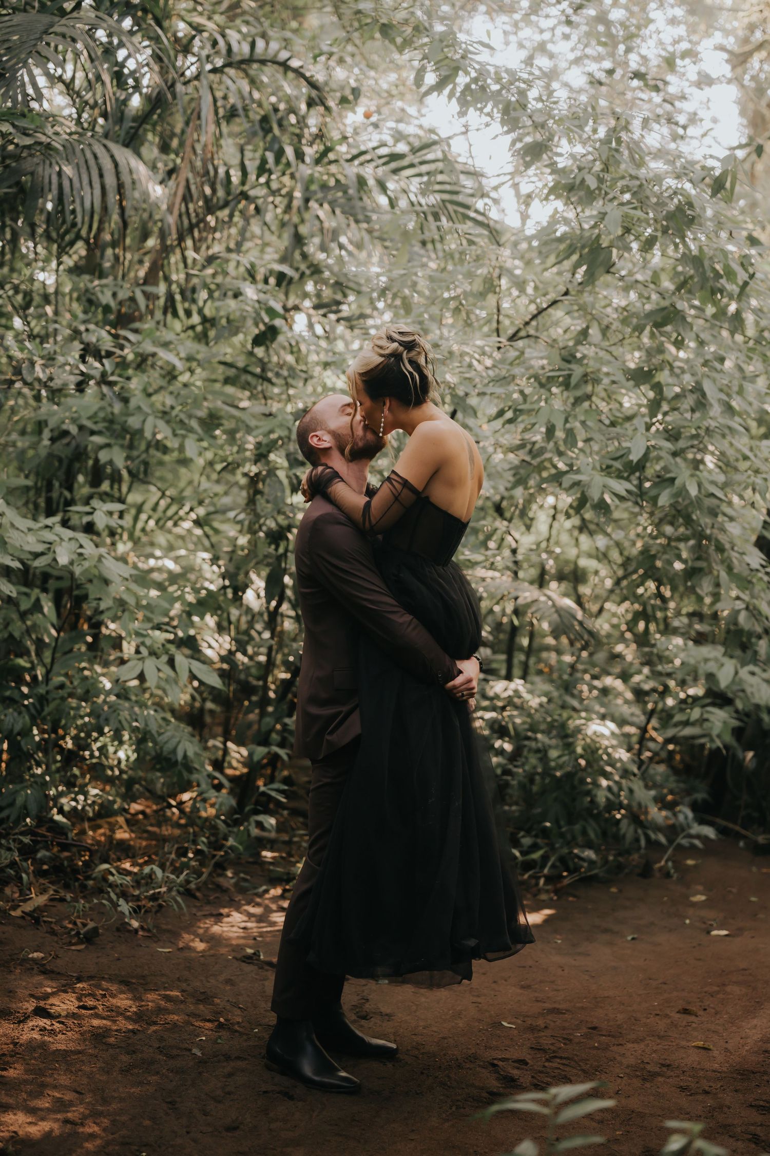 Intimate moment captured in a lush forest setting with fairy lights twinkling in the background.