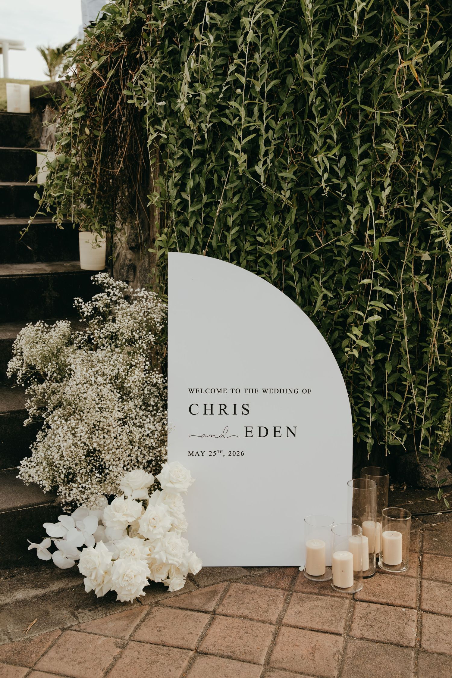 Elegant wedding welcome sign for Chris and Eden, May 25th 2024, surrounded by white flowers and candles.