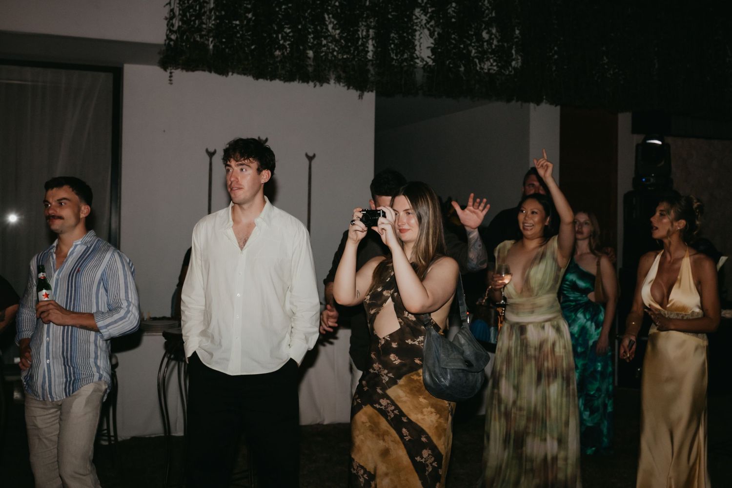 Wedding guests dancing and taking photos at outdoor evening wedding reception party.