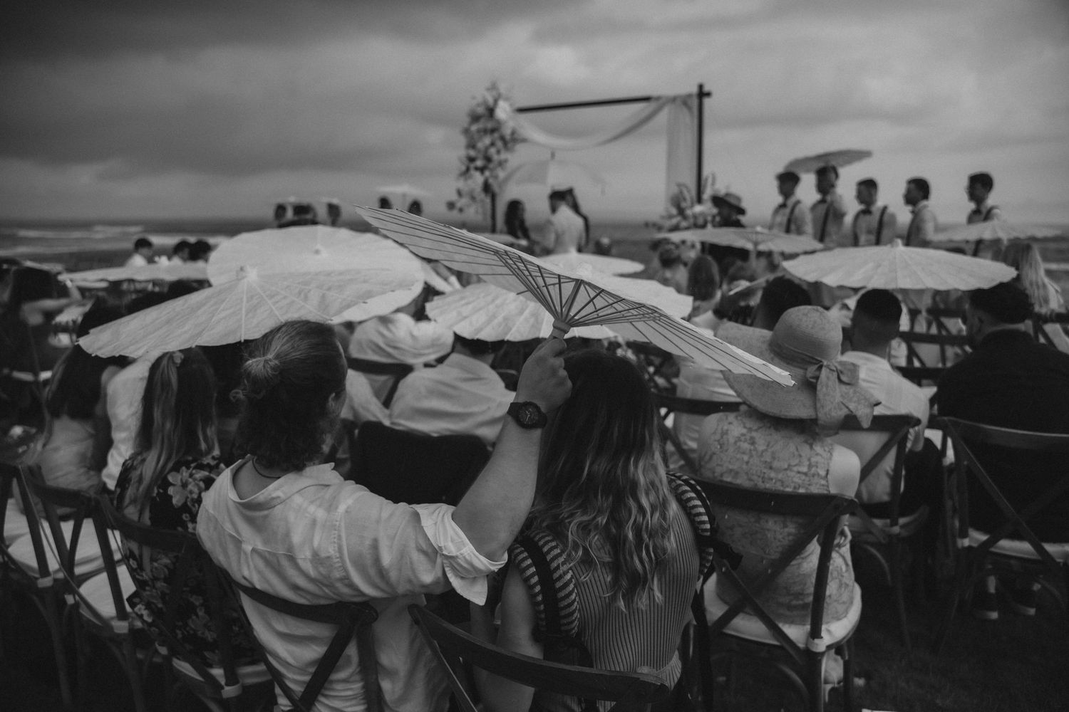 Black and white photo of guests relaxing on lounge chairs at an outdoor event.