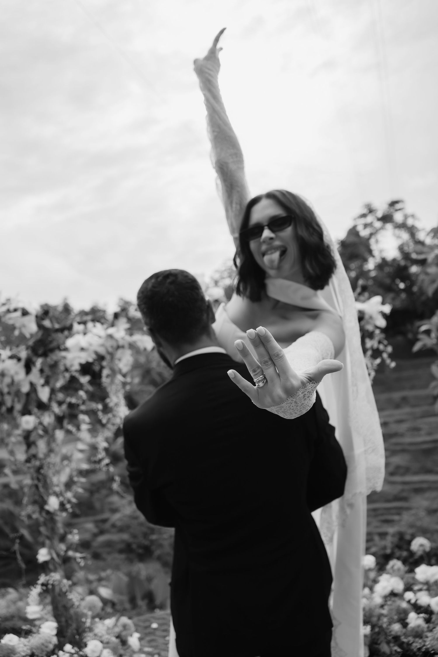 Black and white photo series showing a couple dancing joyfully together in an outdoor garden setting.