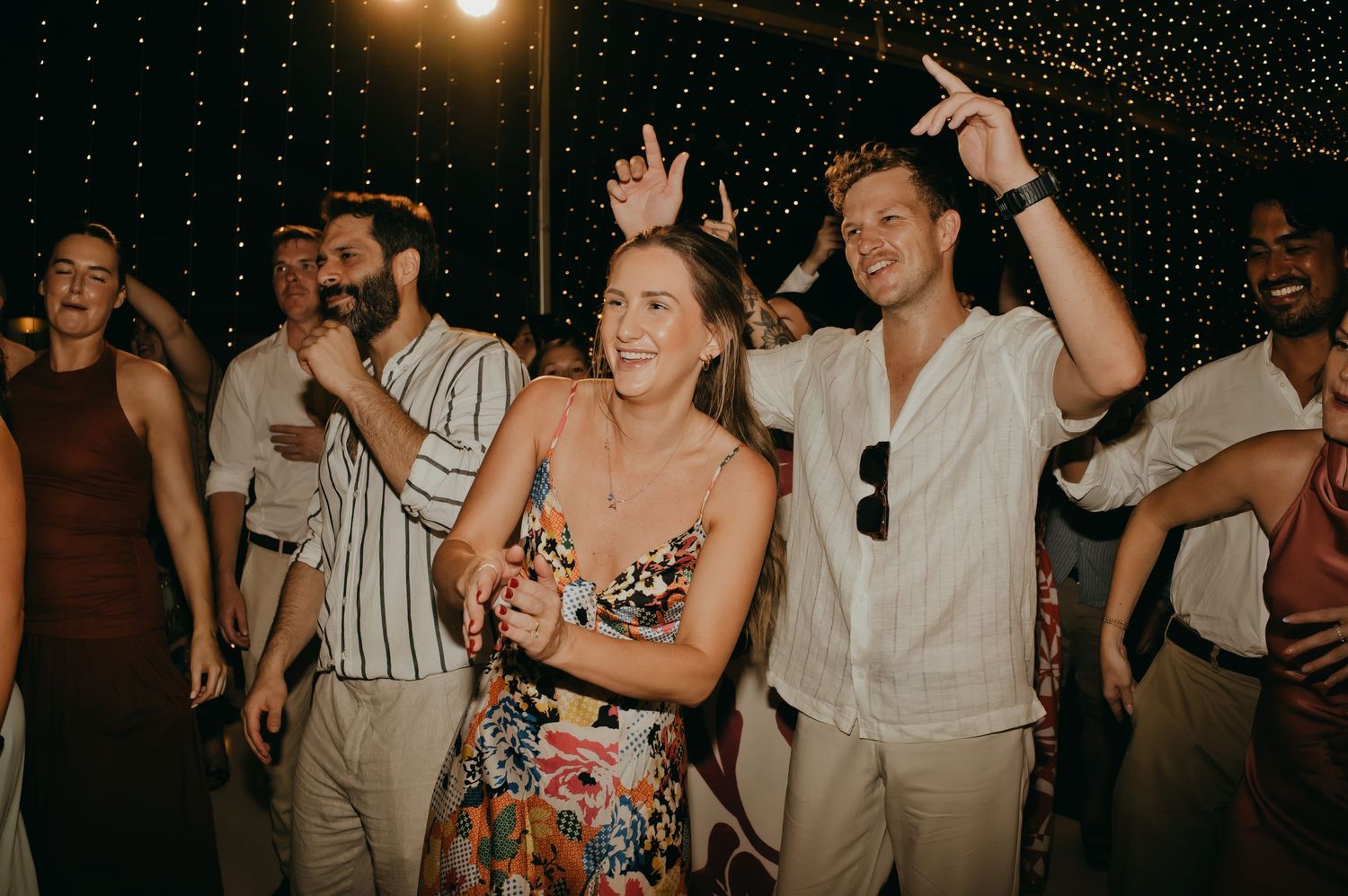 Wedding guests dancing and celebrating on the dance floor at a lively reception party.