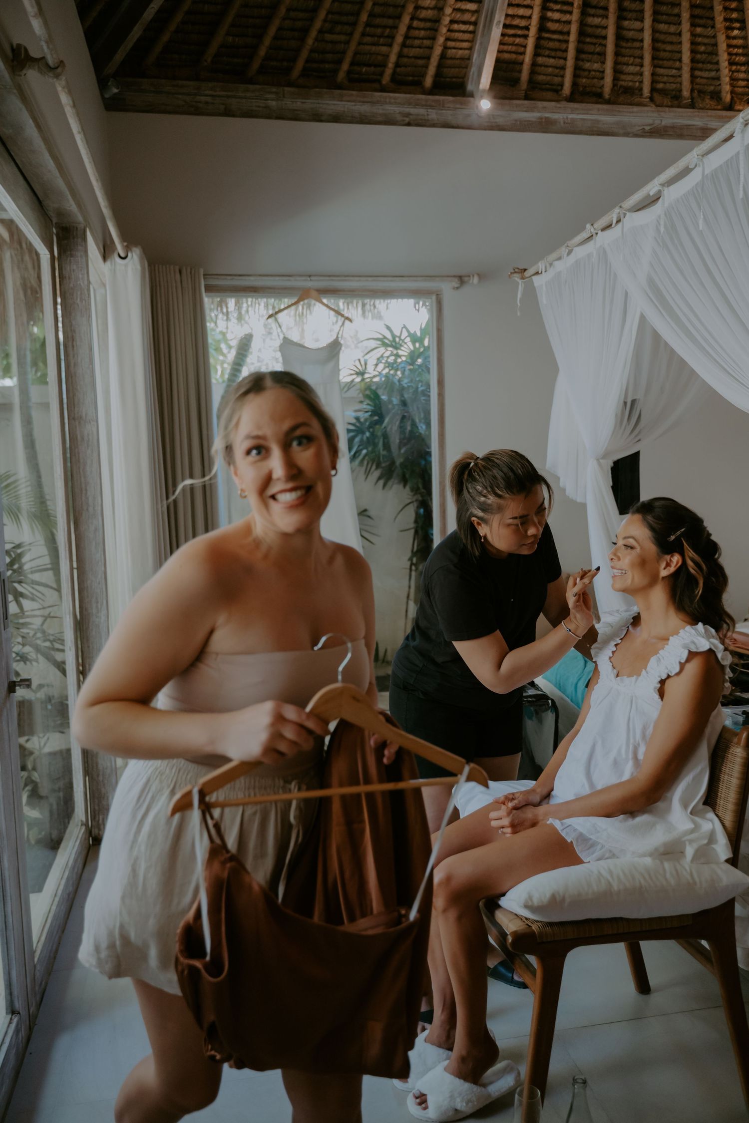 A series of intimate wedding preparation moments captured in a rustic room with white curtains and wooden chairs.