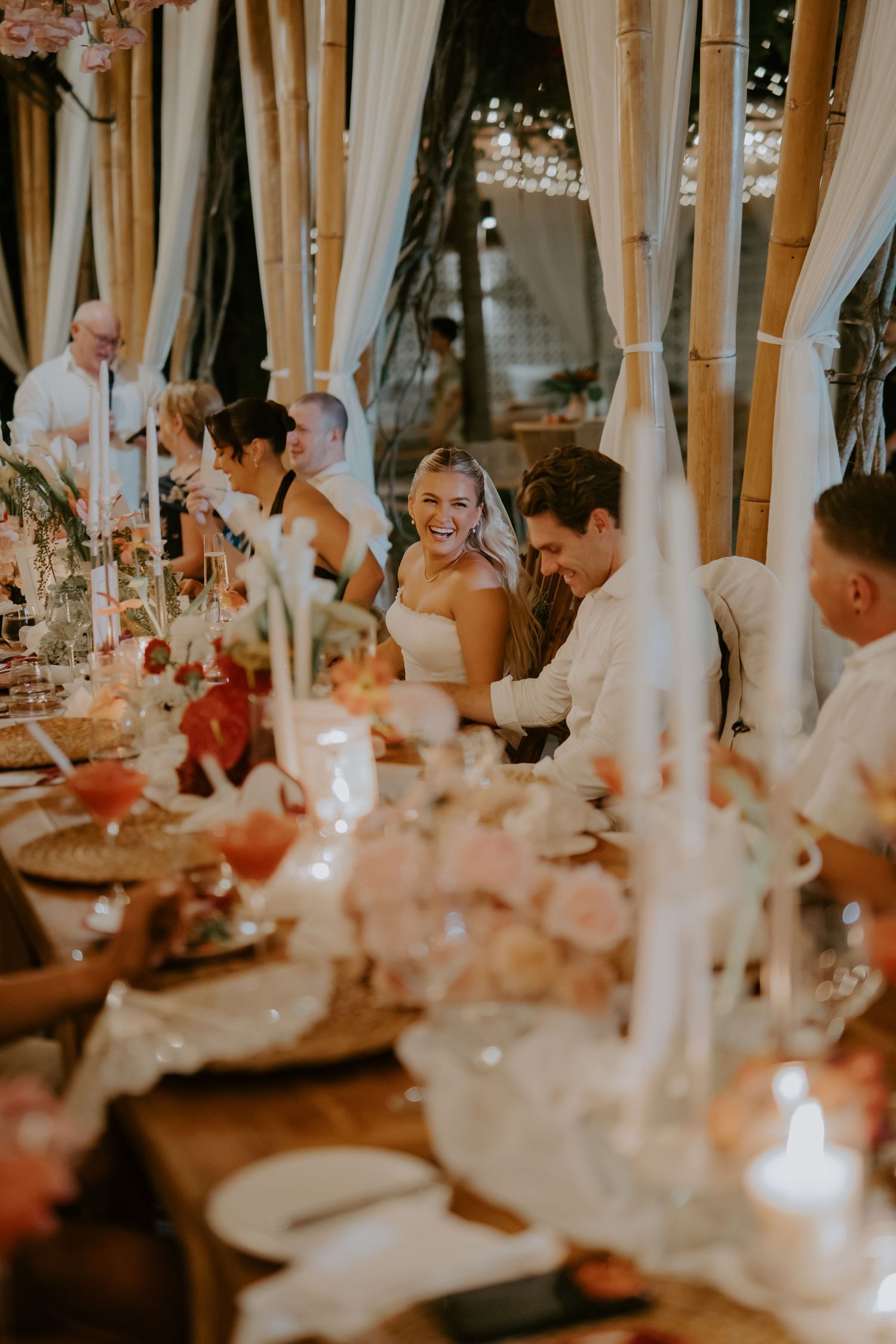 Laughing bride and groom enjoying their wedding reception dinner at a beautifully decorated table.