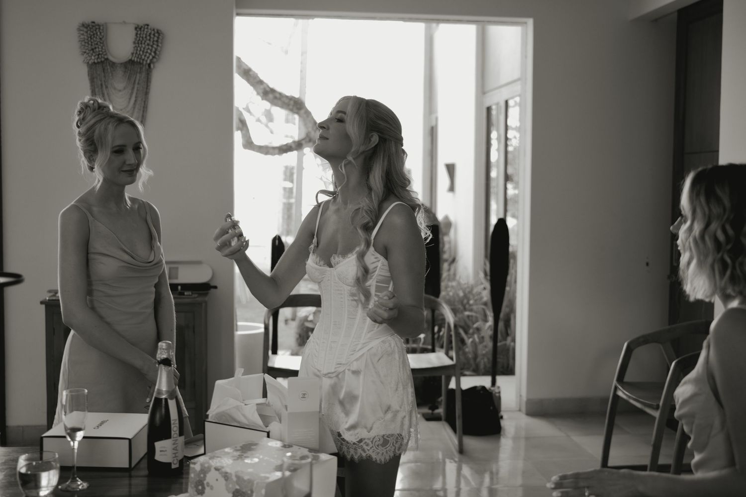Black and white photo of women celebrating indoors, one laughing joyfully while others look on during a festive gathering.