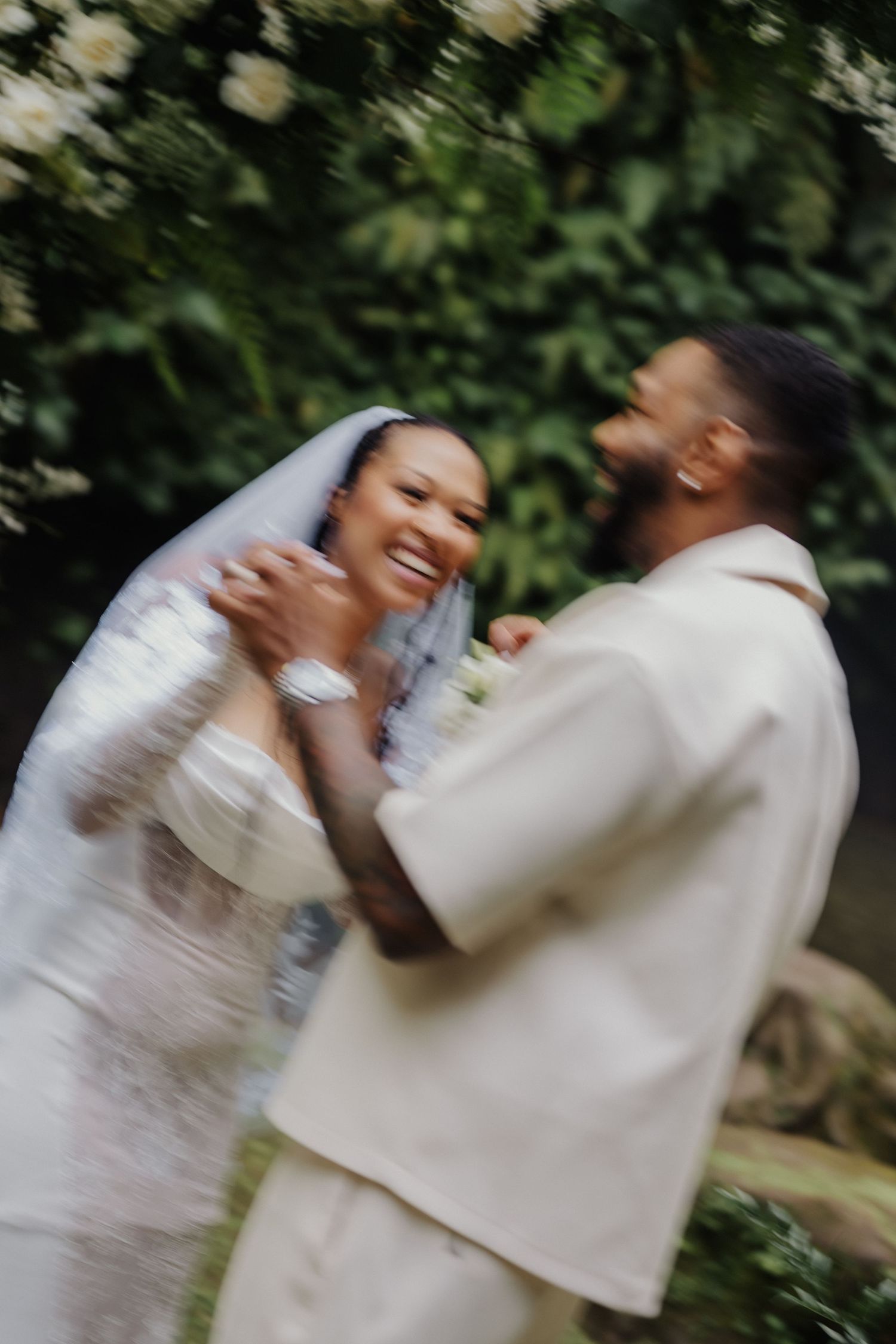 Joyful bride and groom sharing a candid moment in a dreamy motion-blur wedding portrait outdoors.