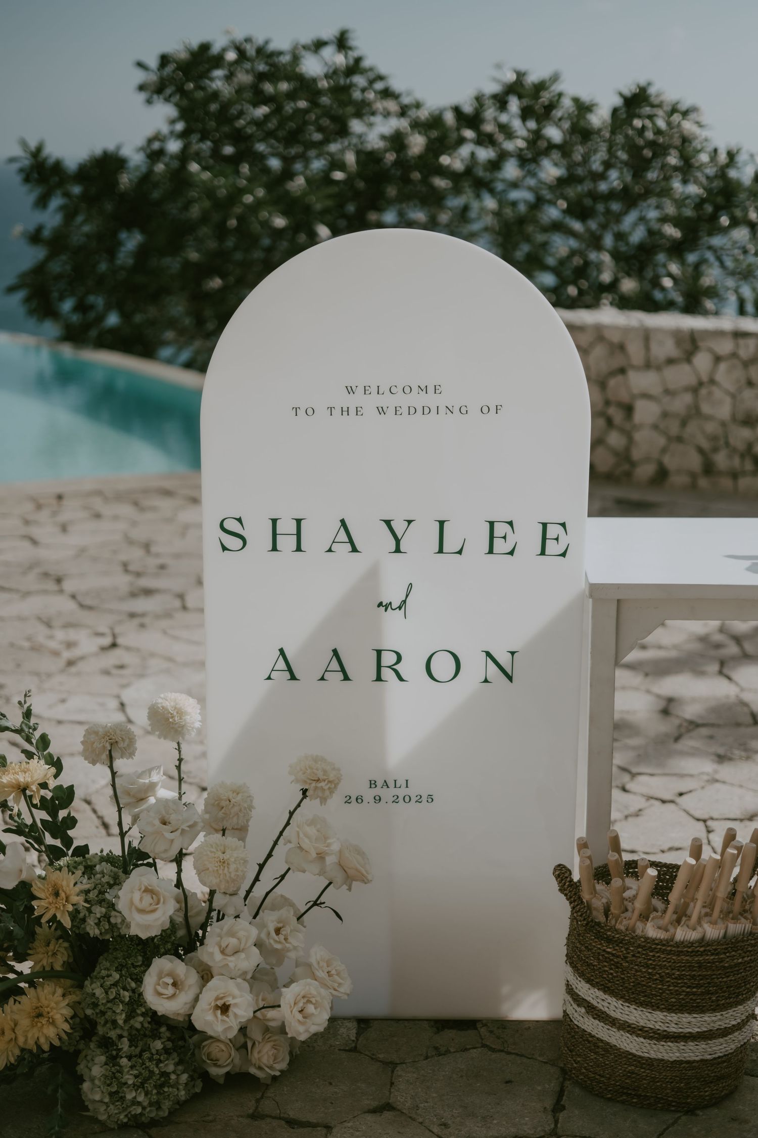 Elegant white wedding welcome sign with floral decorations displays couple's names.