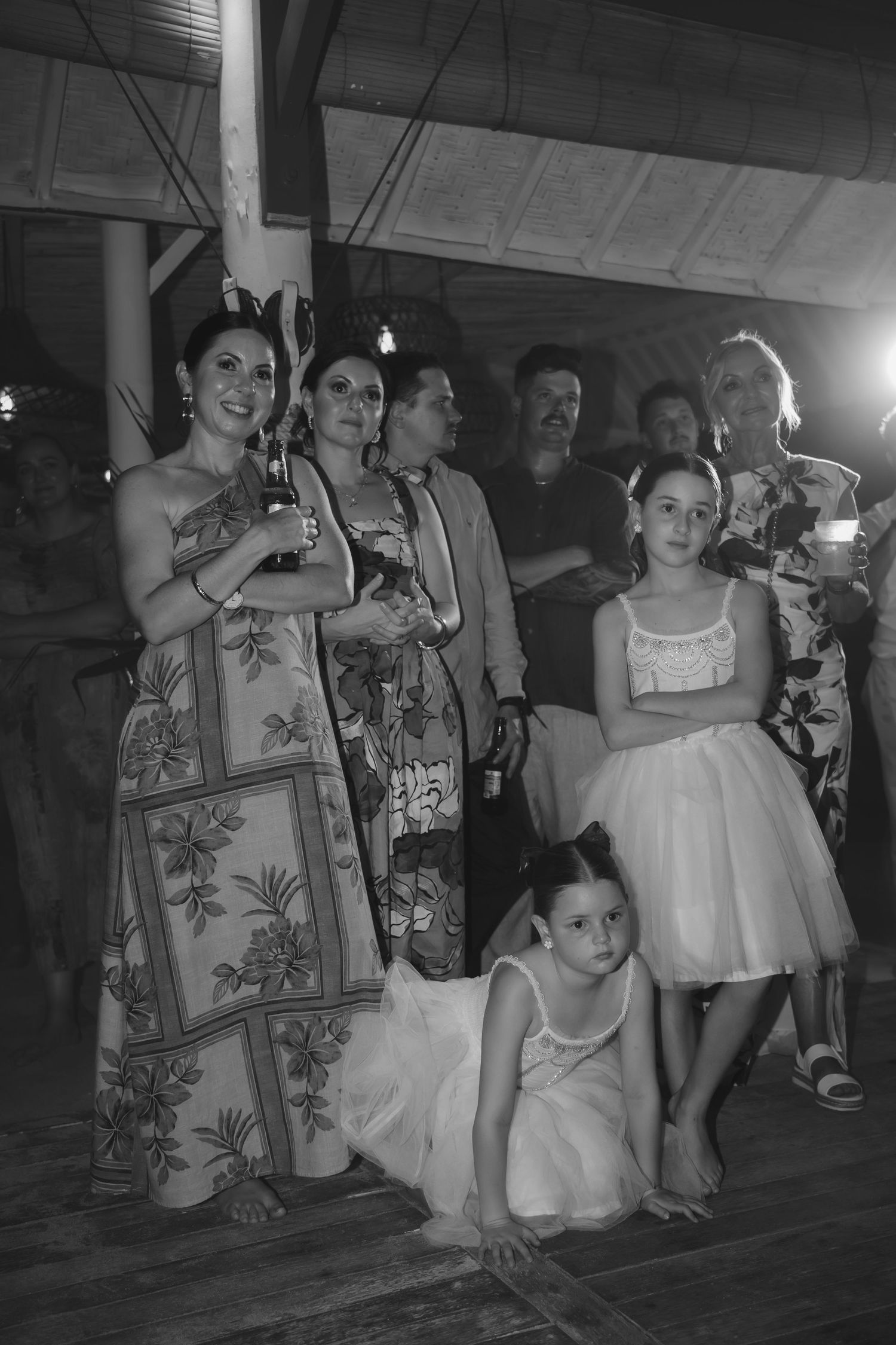 Group photo of wedding guests and children in formal attire at evening reception.