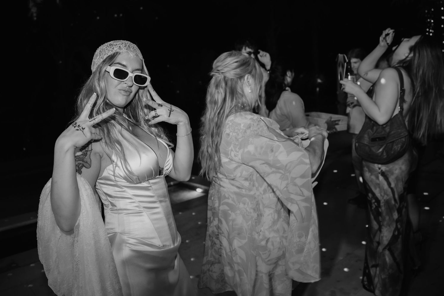 Black and white photo of wedding guests dancing and posing on dance floor at reception.