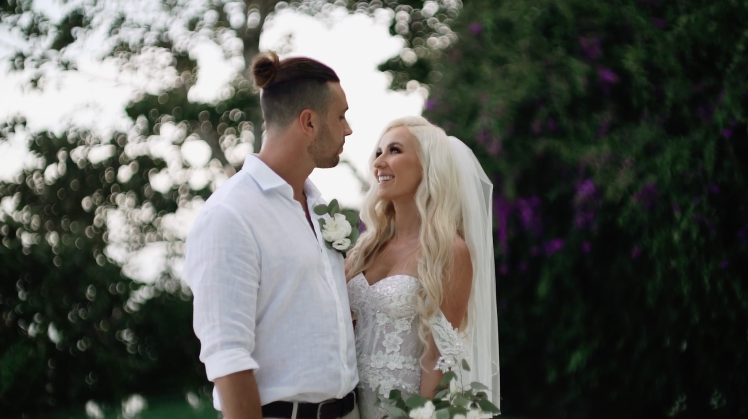 Newlywed couple shares romantic moments in a lush garden setting during their wedding photo session.