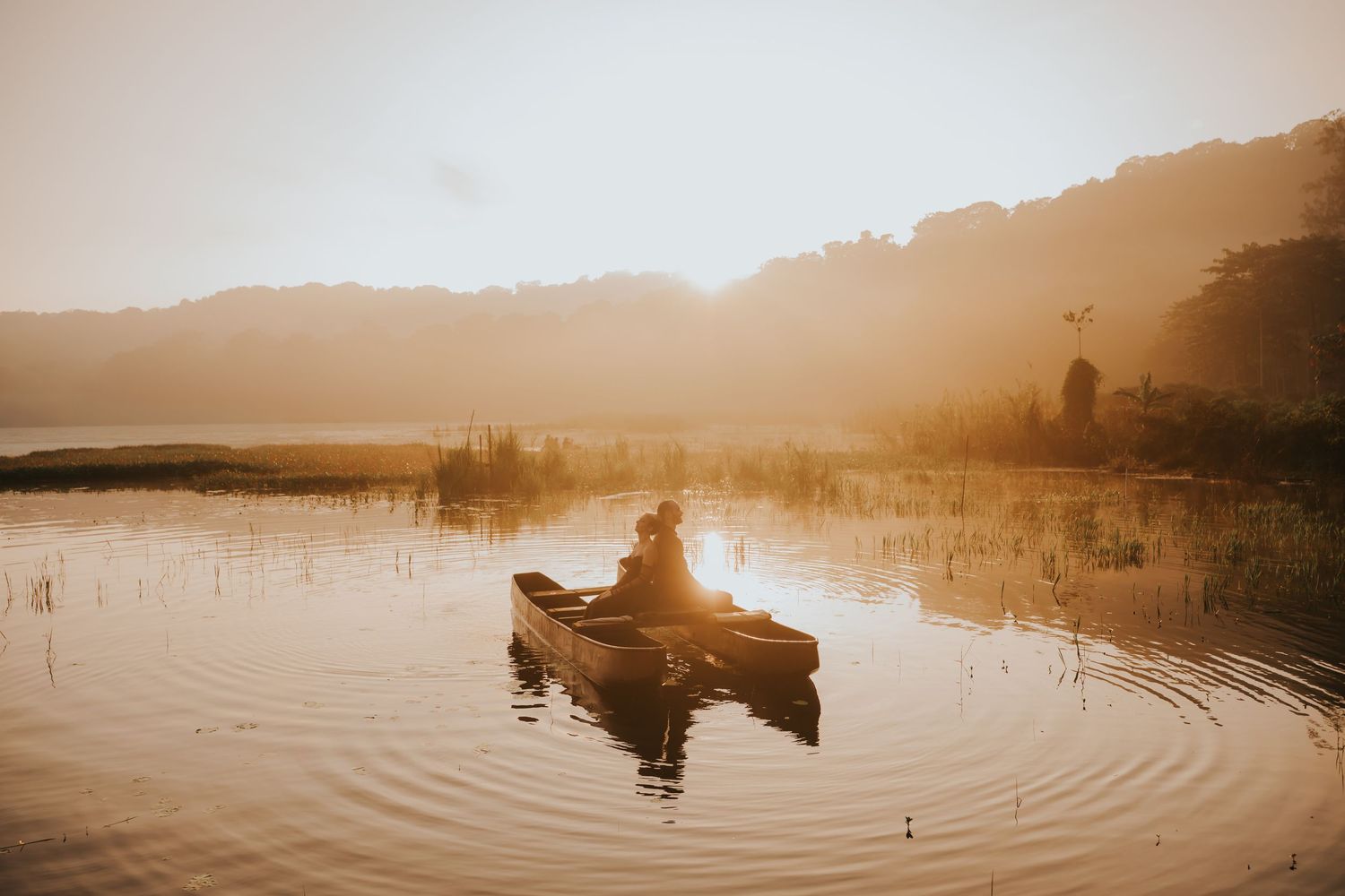 A golden sunset over a tranquil lake creates rippling reflections in sepia tones.