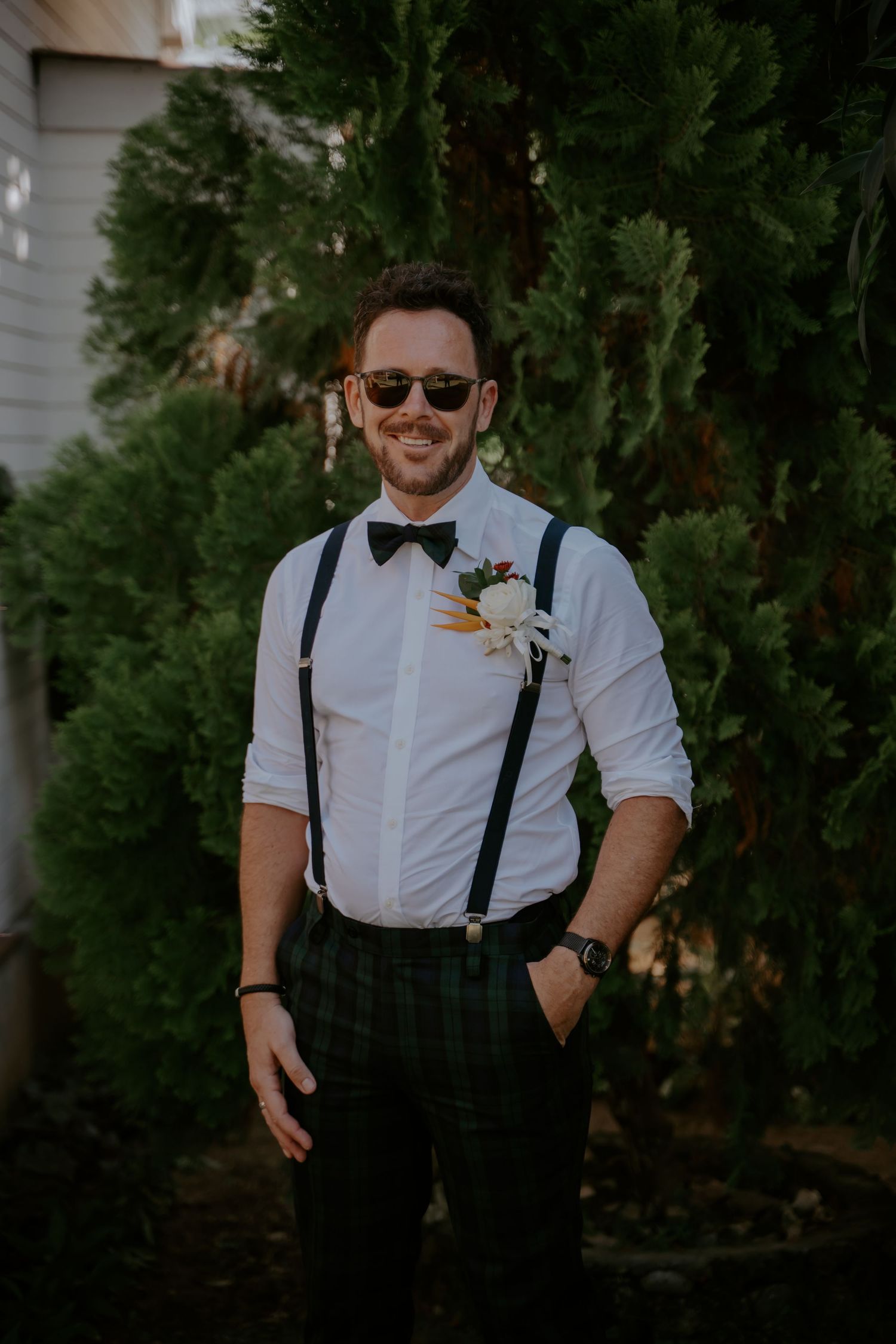 A person in formal attire with suspenders and bow tie smiles outdoors in a series of candid poses.