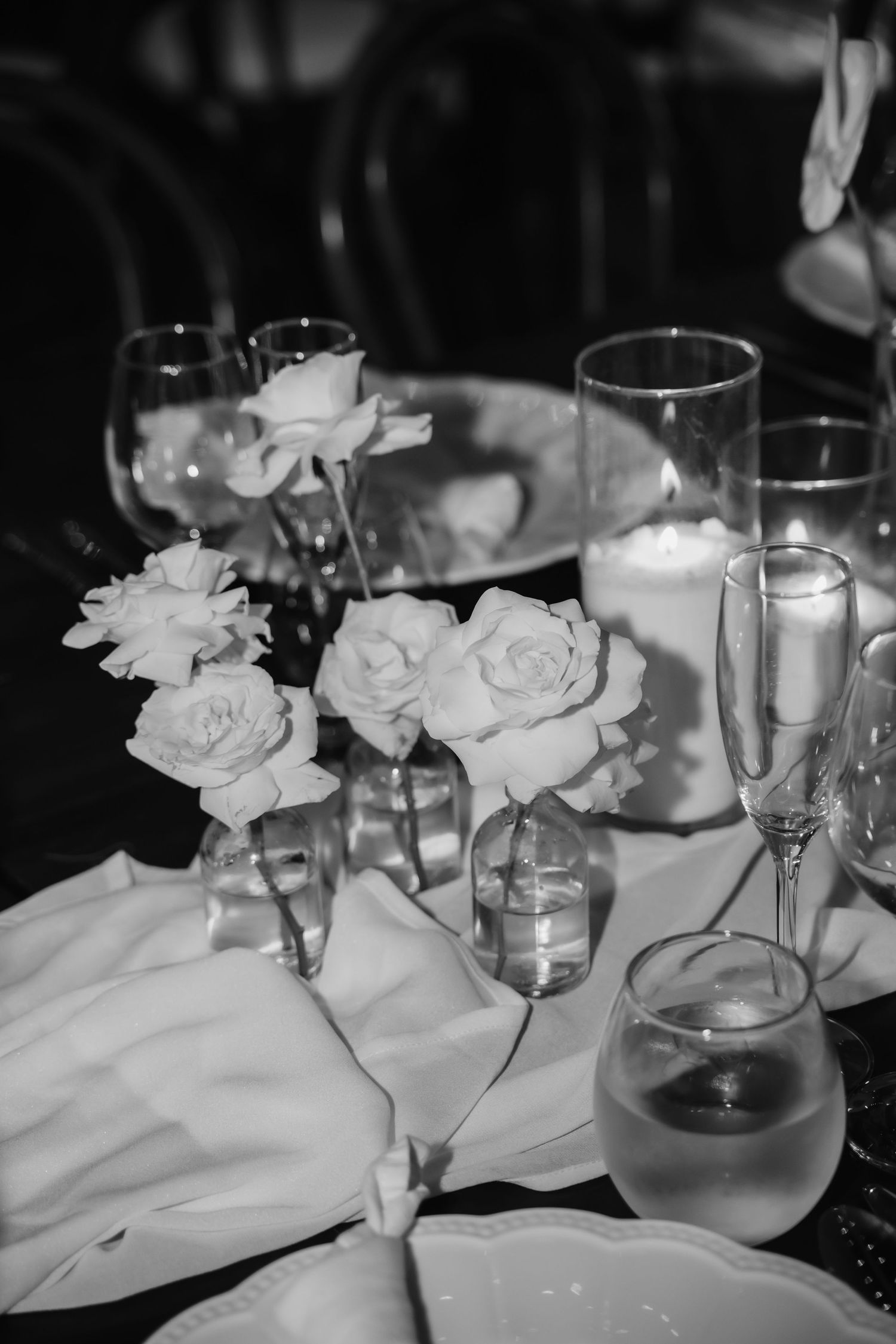 Elegant black and white wedding table with roses, candles, and champagne glasses.