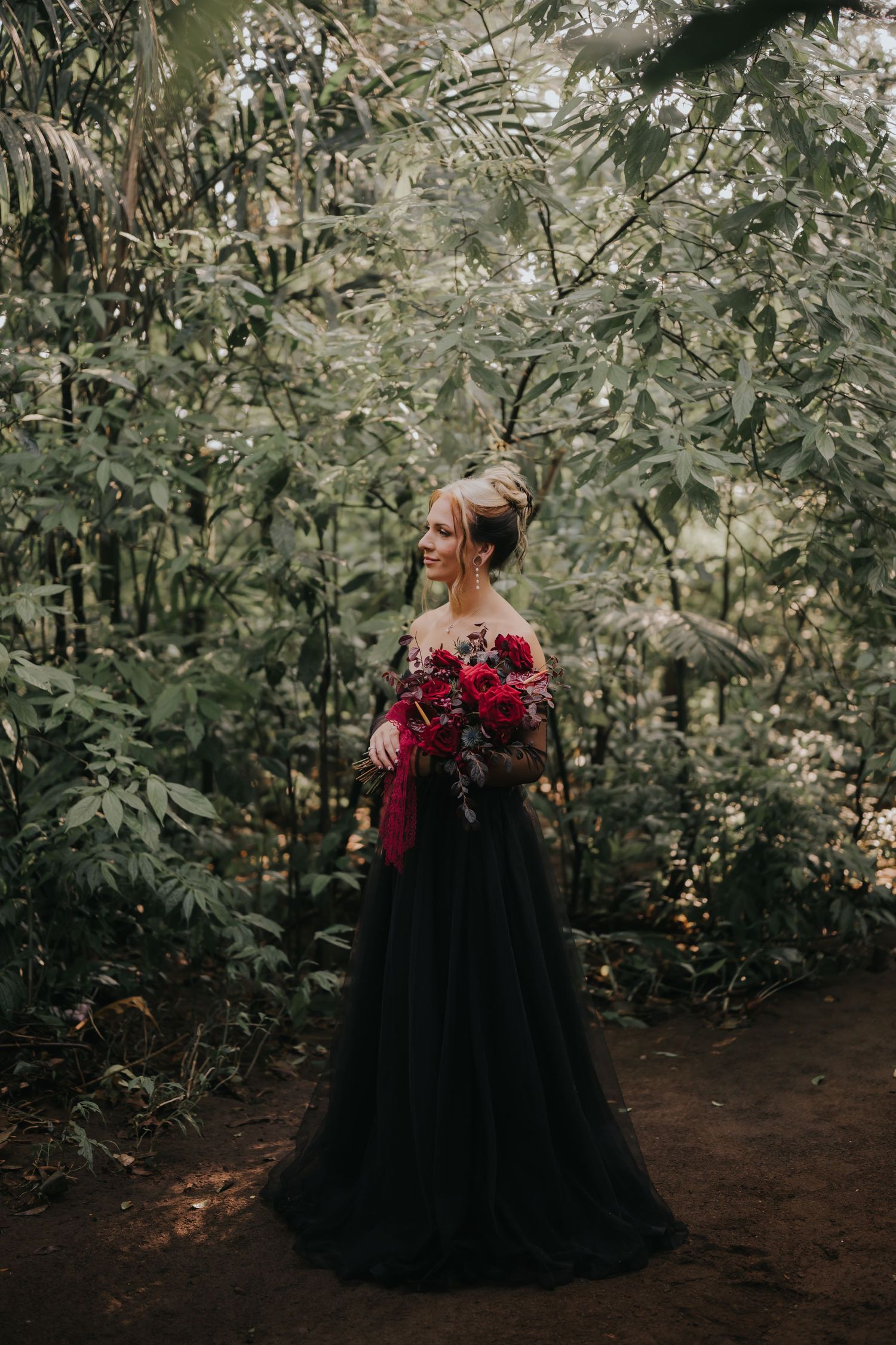 A series of ethereal forest portraits showing a person in a flowing black gown holding deep red flowers.