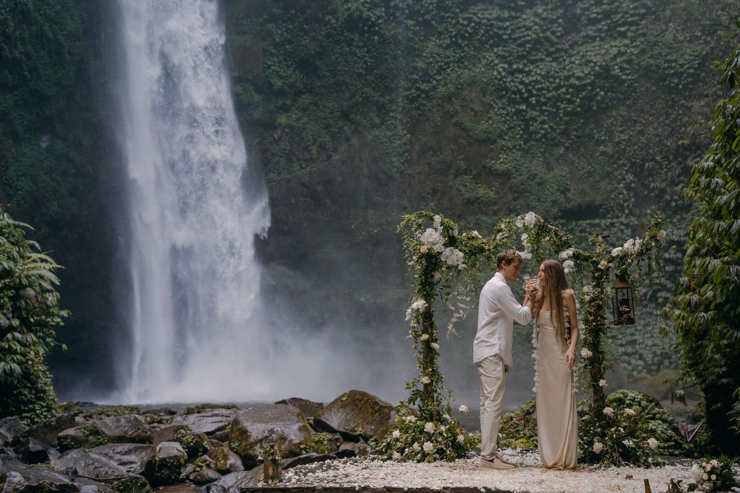 A majestic waterfall cascades down a rocky cliff surrounded by lush tropical vegetation in Hawaii.