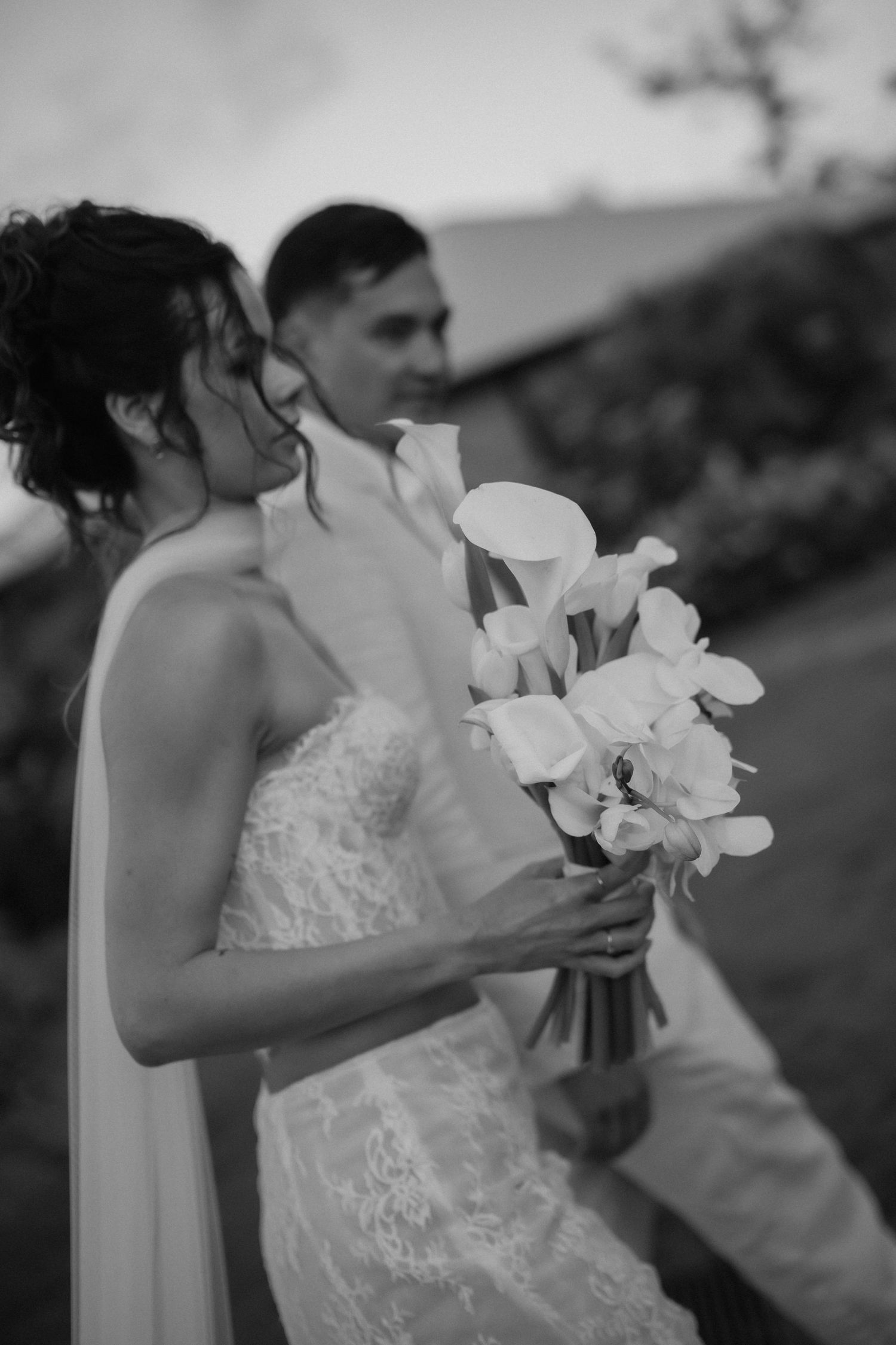 Black and white wedding photo series showing close-up details of a bride's bouquet and dress in natural outdoor lighting.