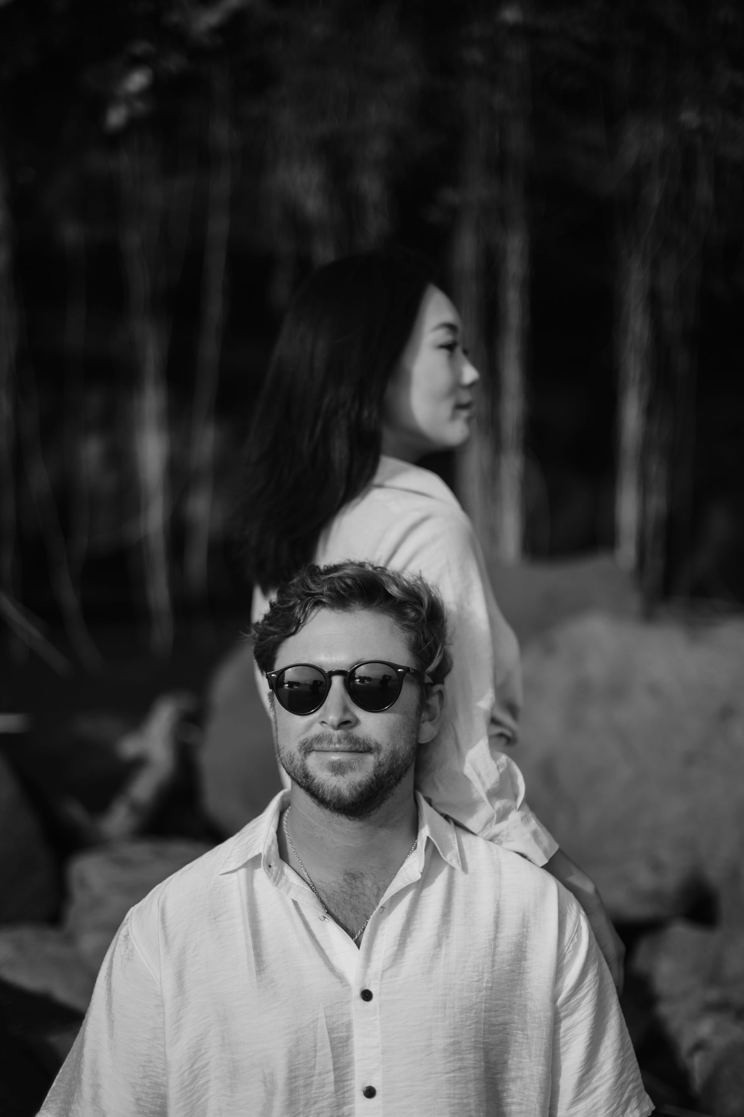 Black and white portrait series showing person in white shirt and sunglasses in outdoor forest setting.