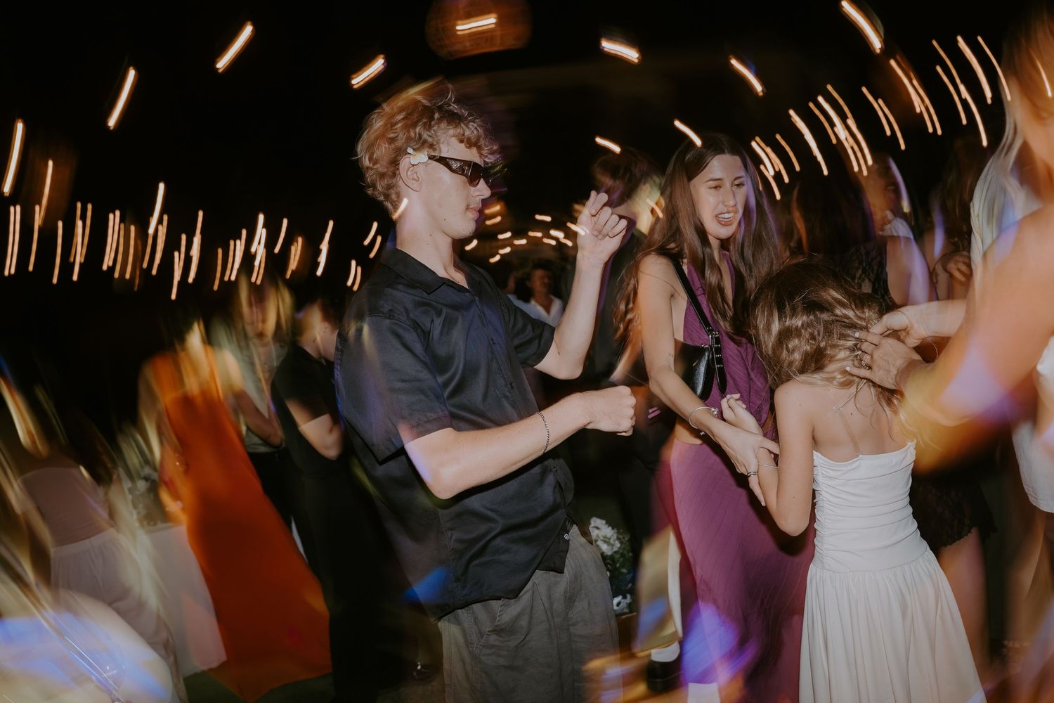 Guests dancing energetically at a wedding reception with dynamic motion blur lighting effects.