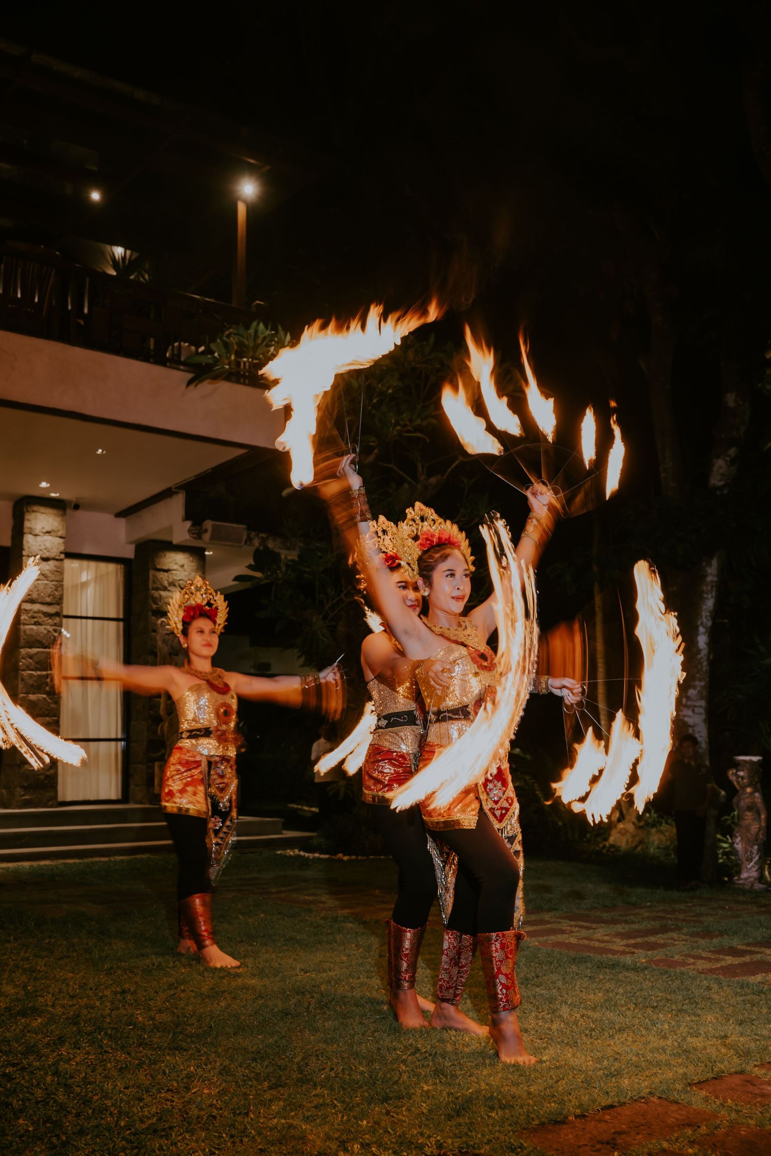 Traditional Balinese fire dancers performing with spinning flames at a nighttime outdoor event.