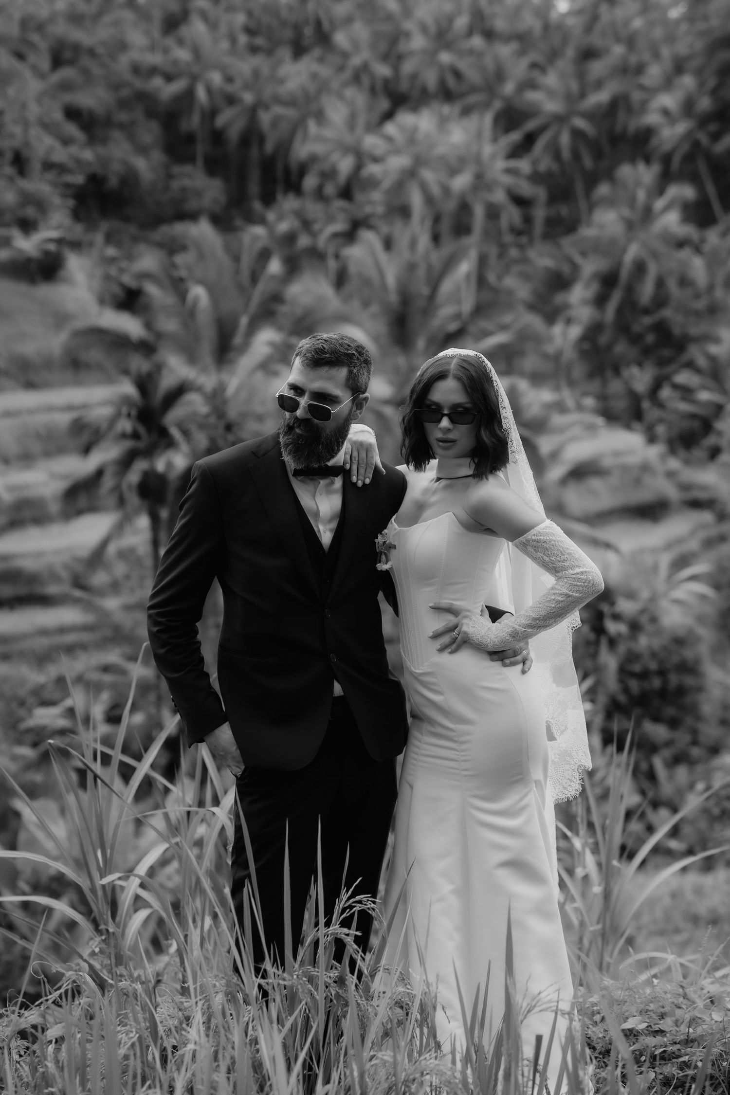 A wedding party poses together on a grassy hillside in black and white formal attire.