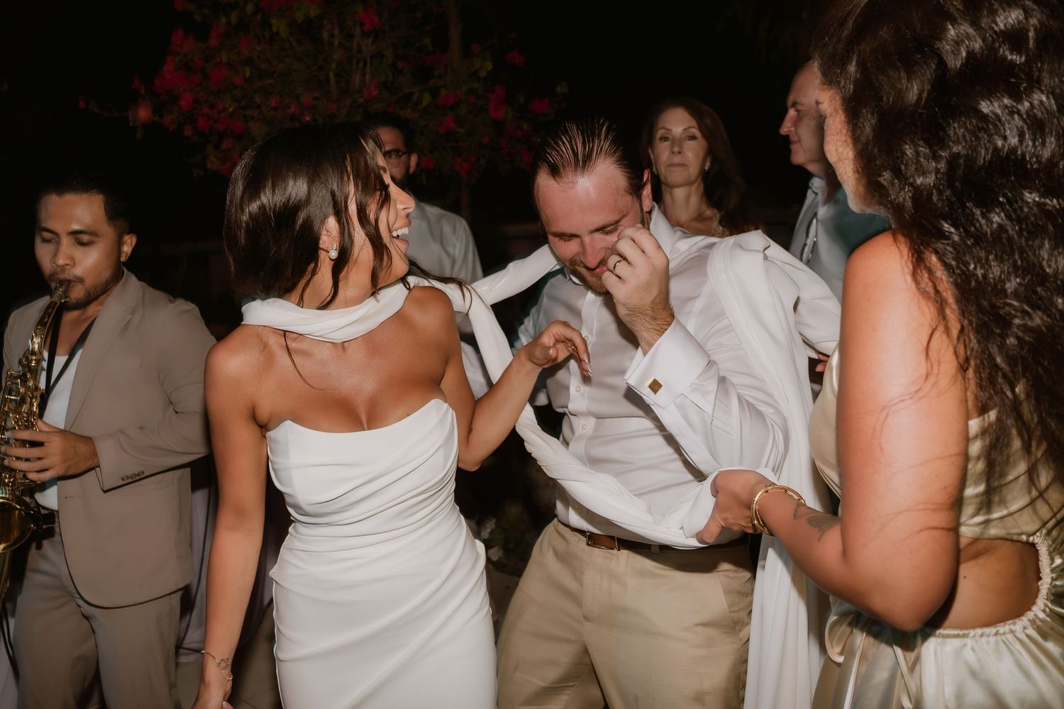 Bride and groom dance energetically together at their lively outdoor wedding reception with live band.