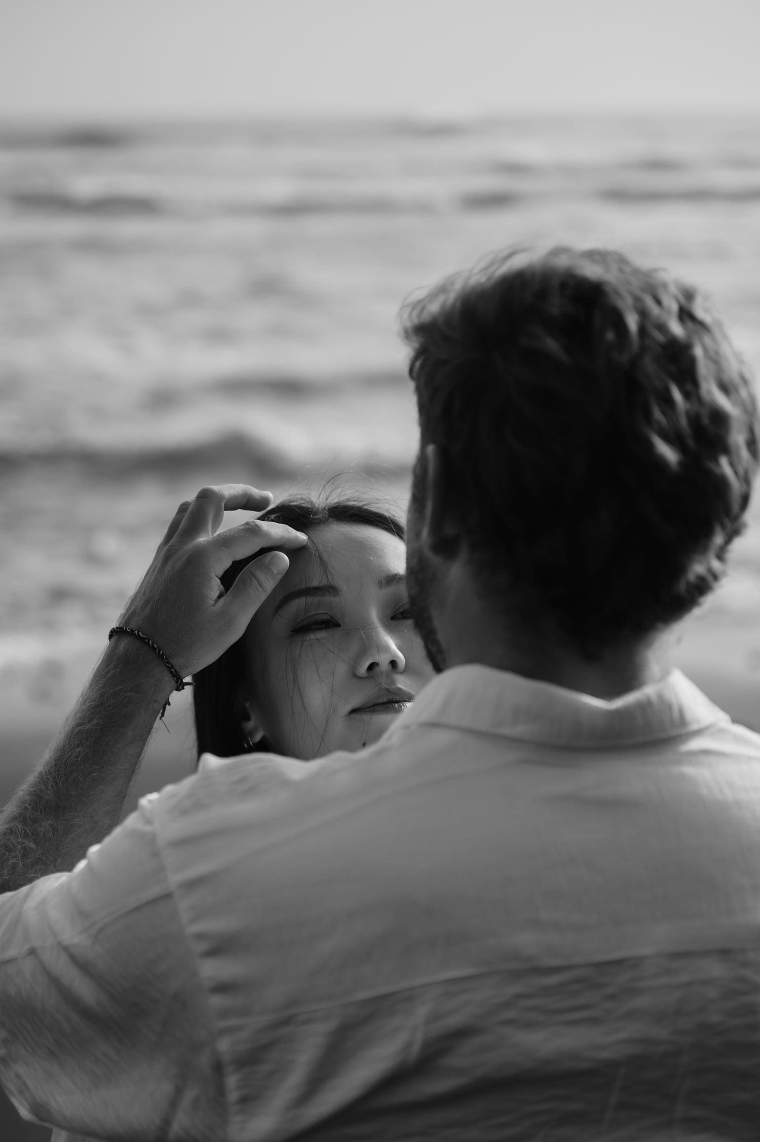 A black and white photo sequence shows a couple embracing while looking out at the ocean.