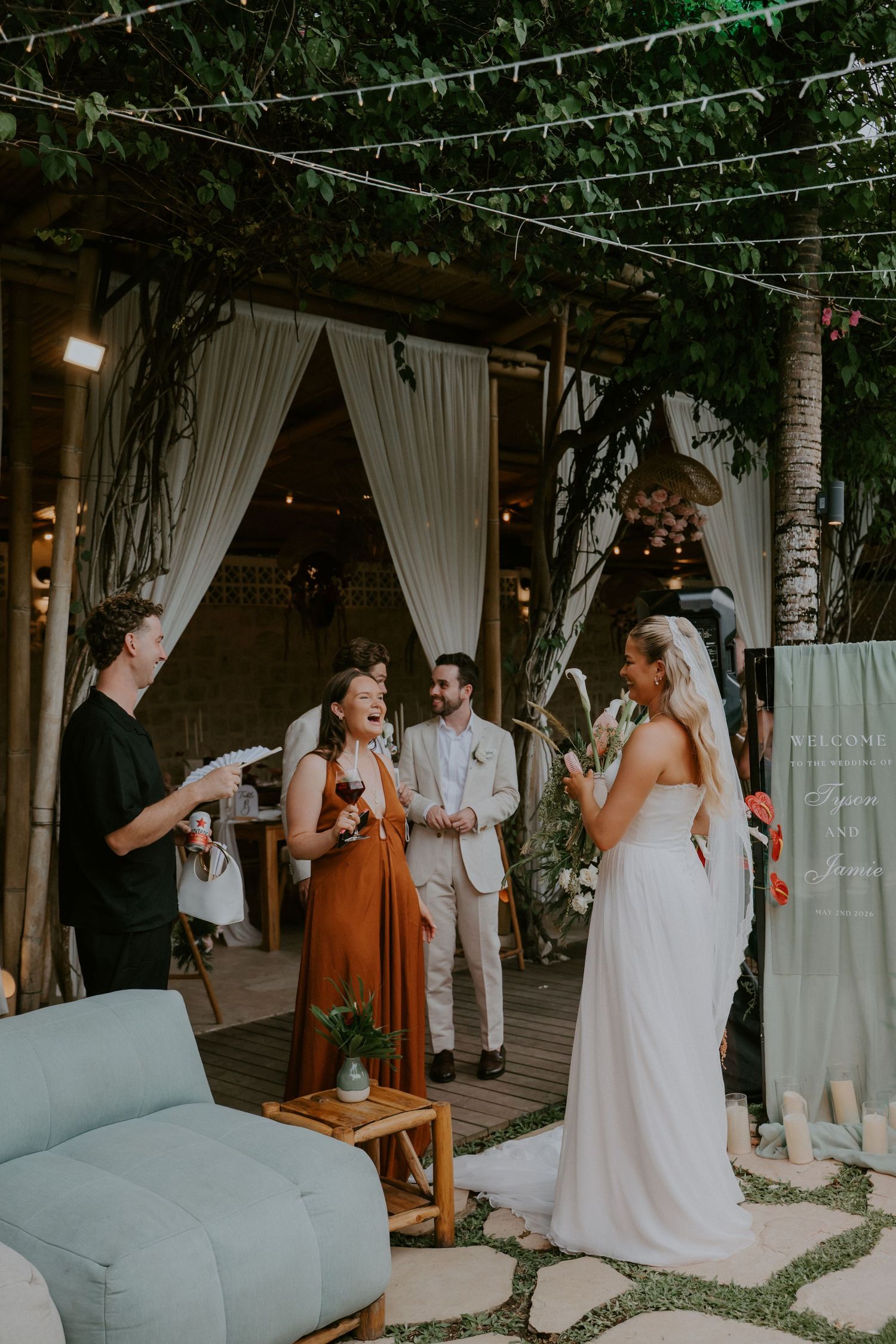 Bride in white gown laughing with guests at an outdoor boho wedding reception.