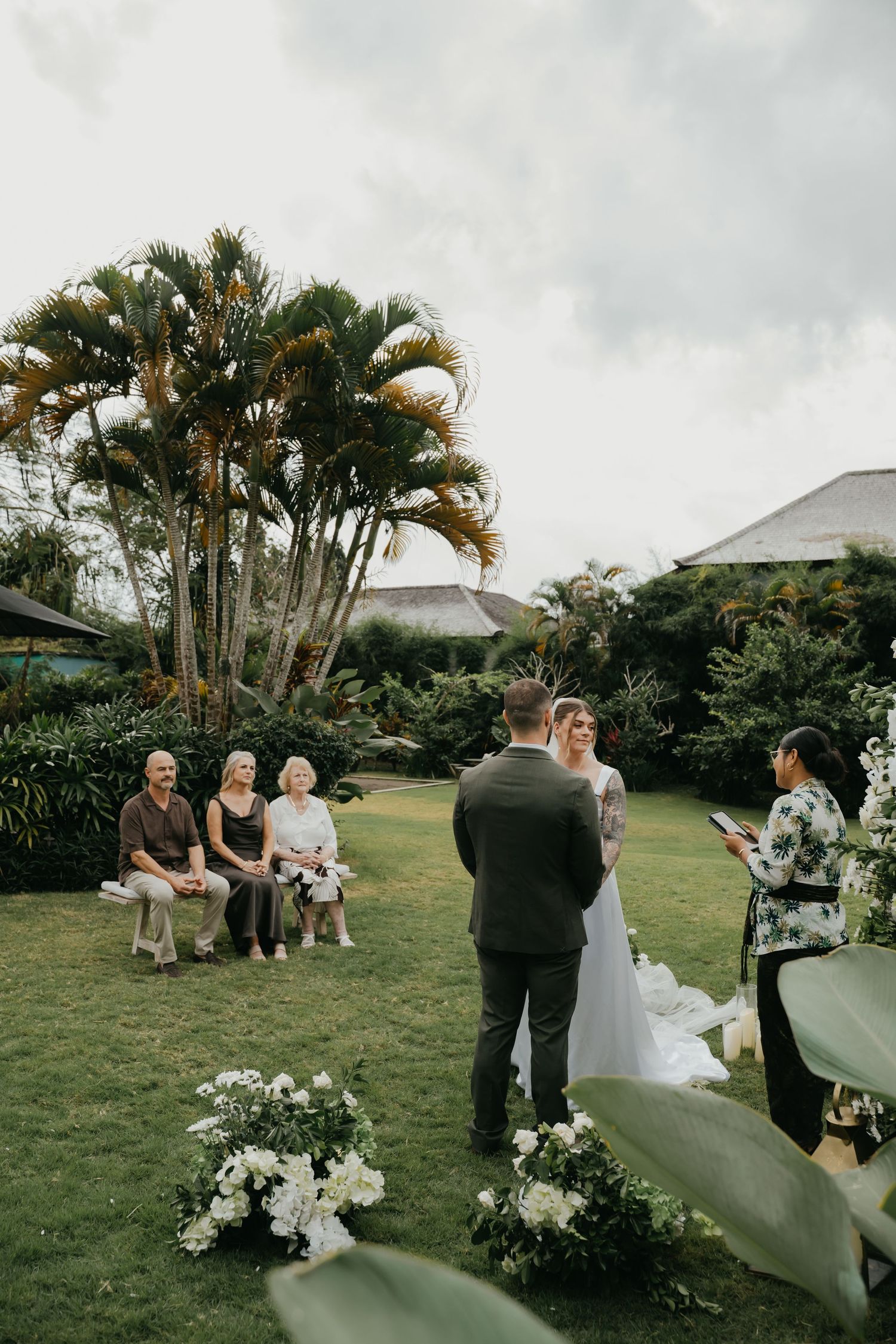 Bride and groom during intimate outdoor garden wedding ceremony with seated family guests.
