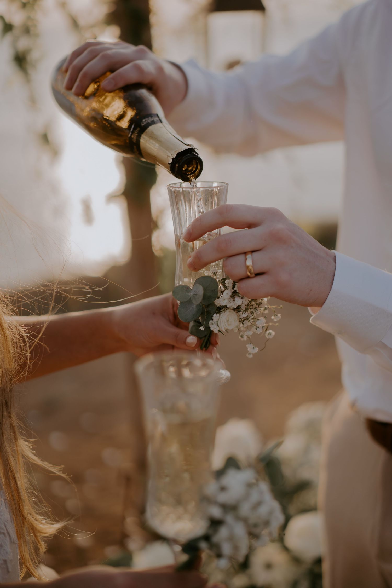 Champagne being poured into a glass with delicate floral decorations at an elegant wedding celebration.