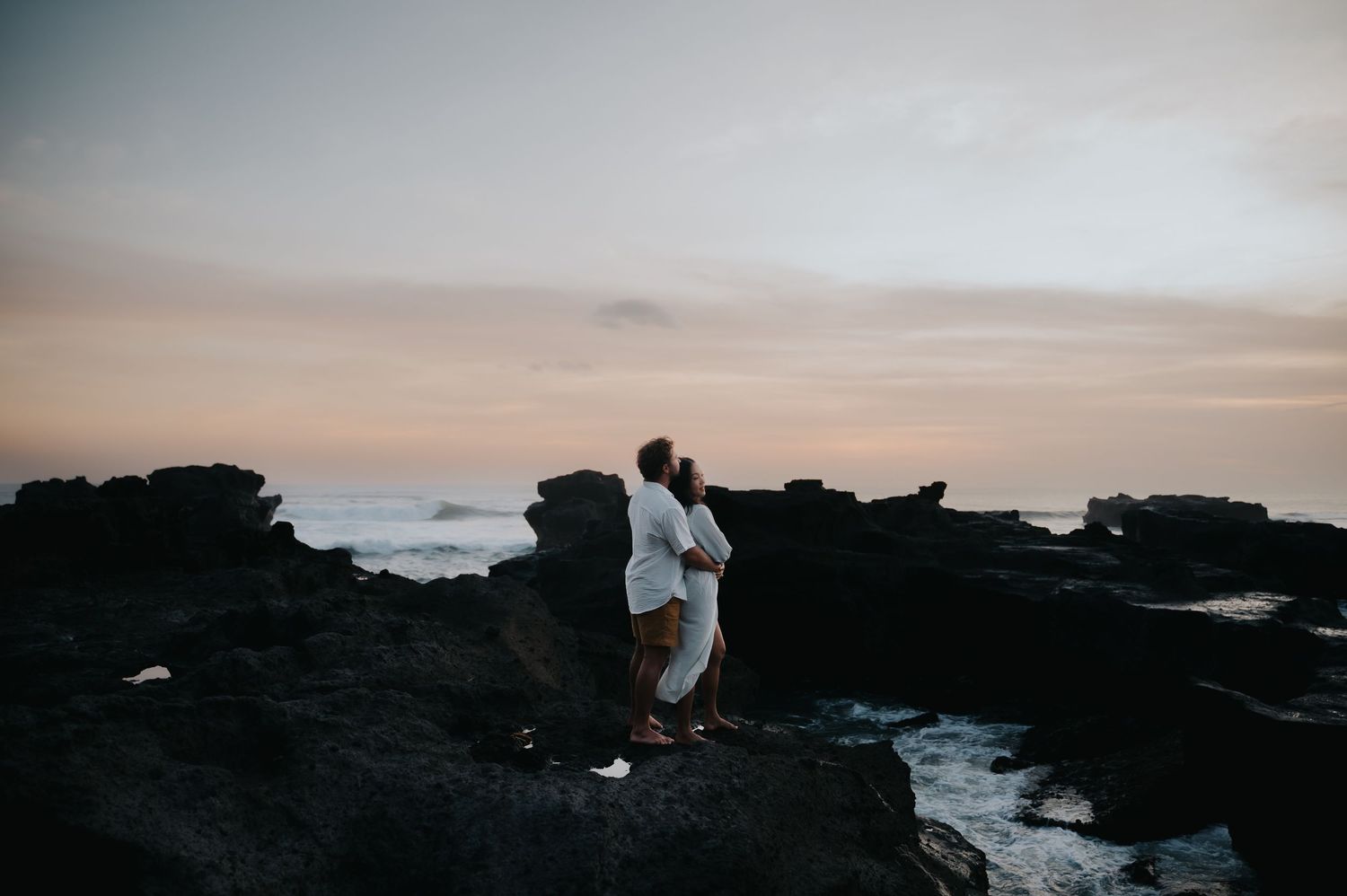 A scenic coastal landscape with rocky cliffs and crashing waves against a moody sunset sky.