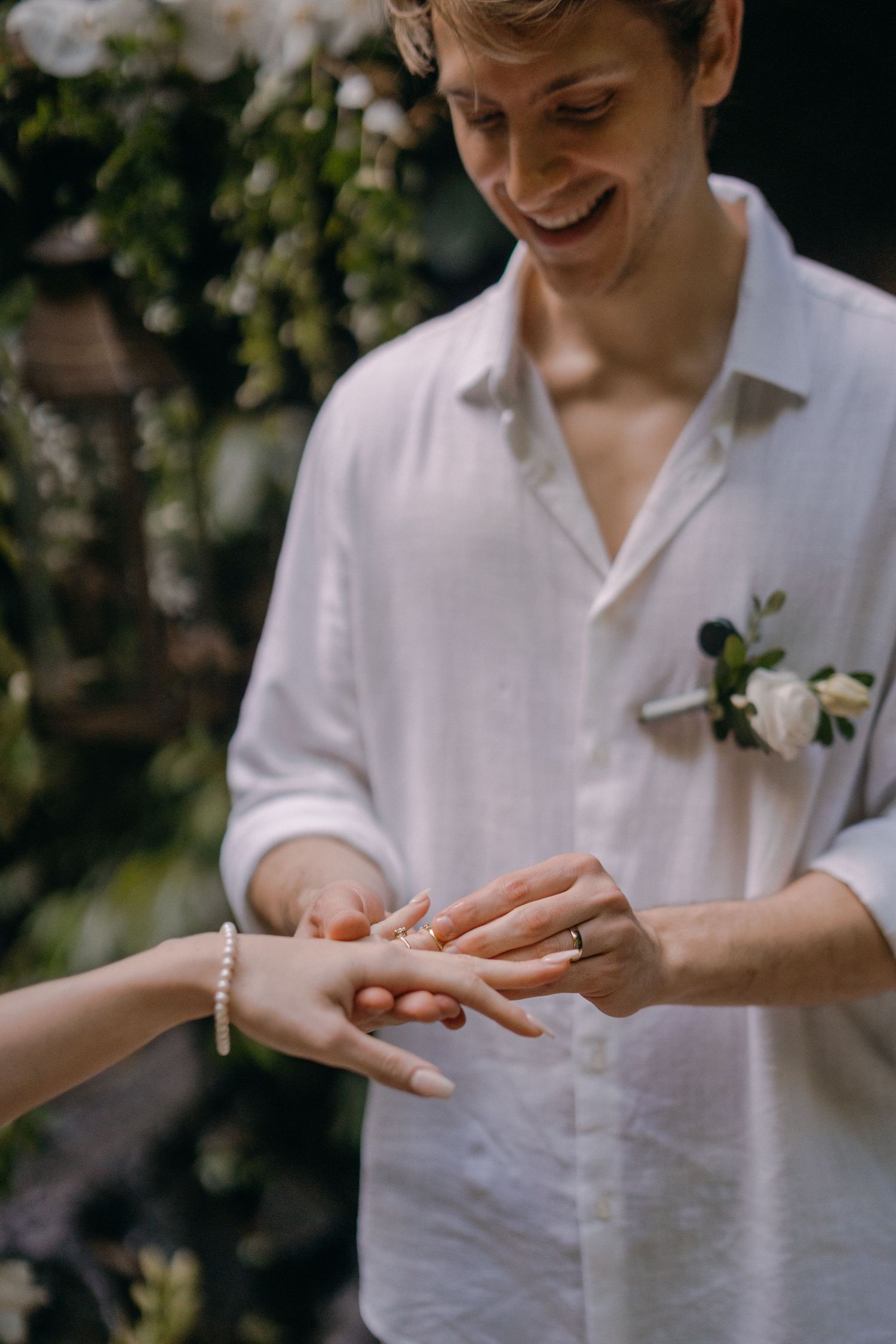 A sequence of hands showing a ring being placed on a finger during an outdoor wedding ceremony.